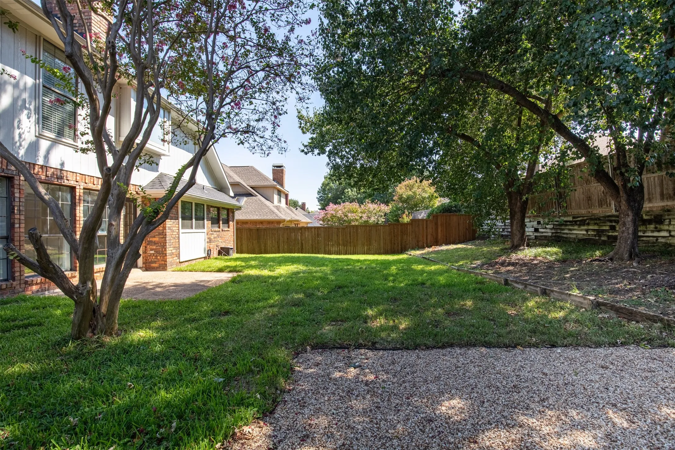 Backyard enclosed with mature shade trees and privacy fencing.
