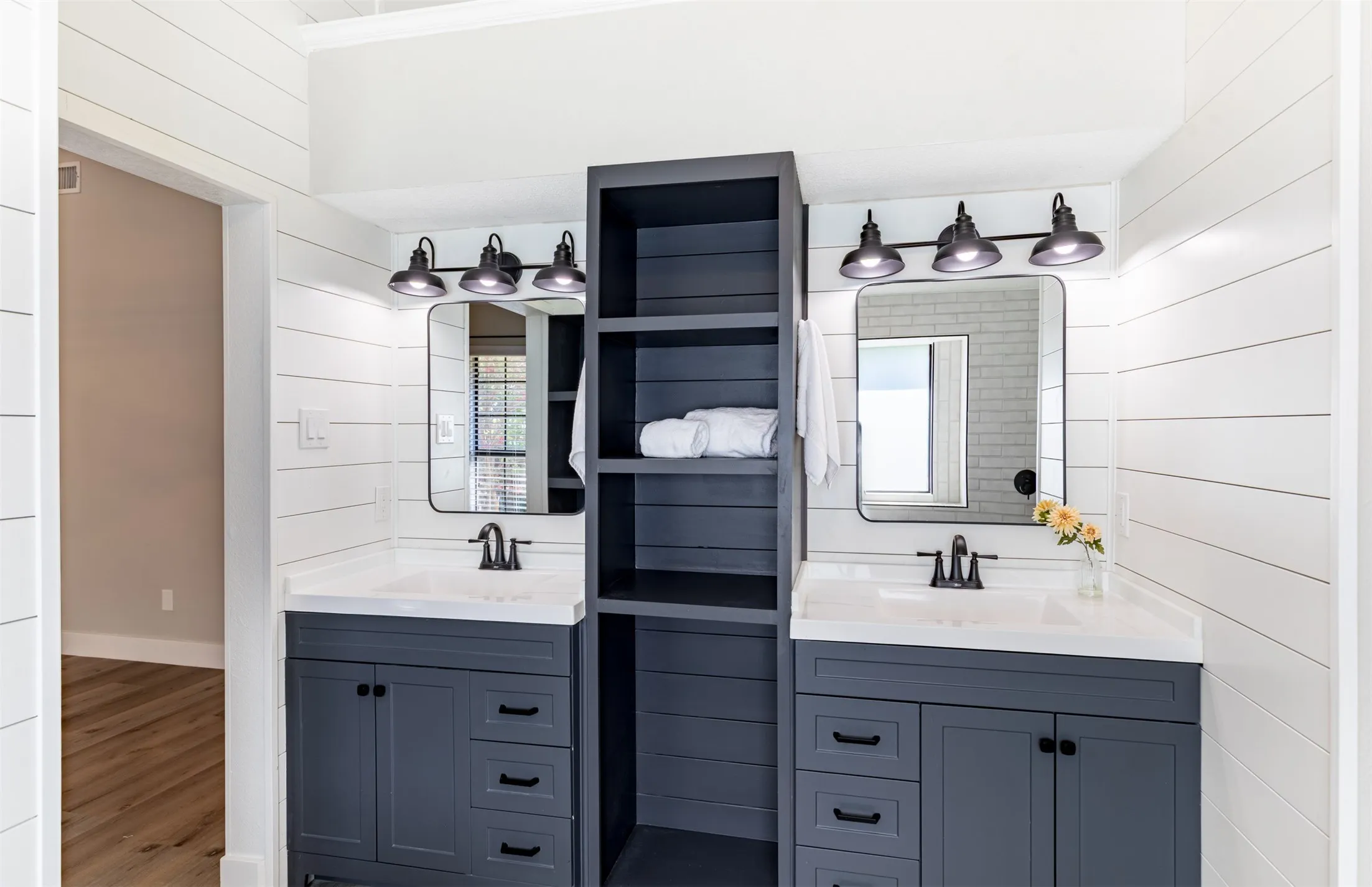 En-suite bath with dual sinks and linen storage.