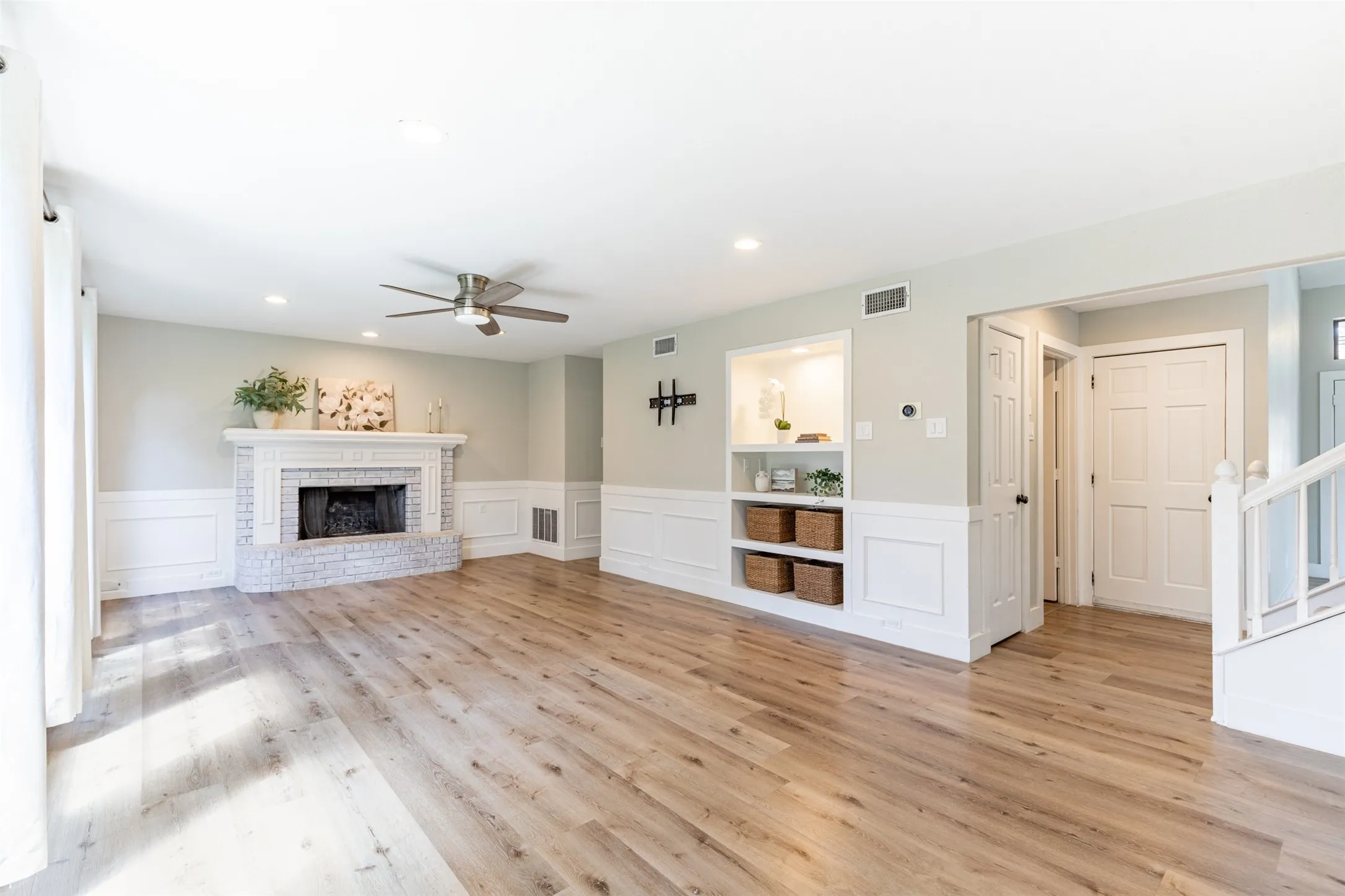 Family room with custom built-ins with lighting and entry too half bath.