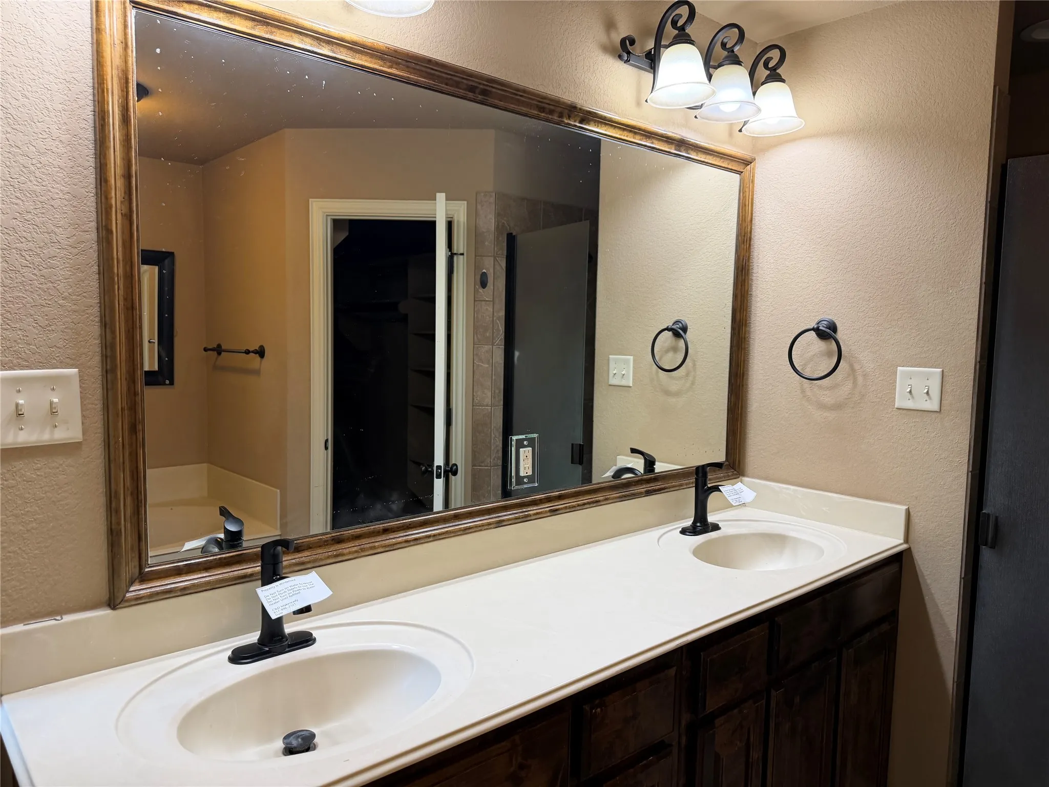 Double vanity with integrated sinks, dark wood-finish cabinetry, and matte black fixtures