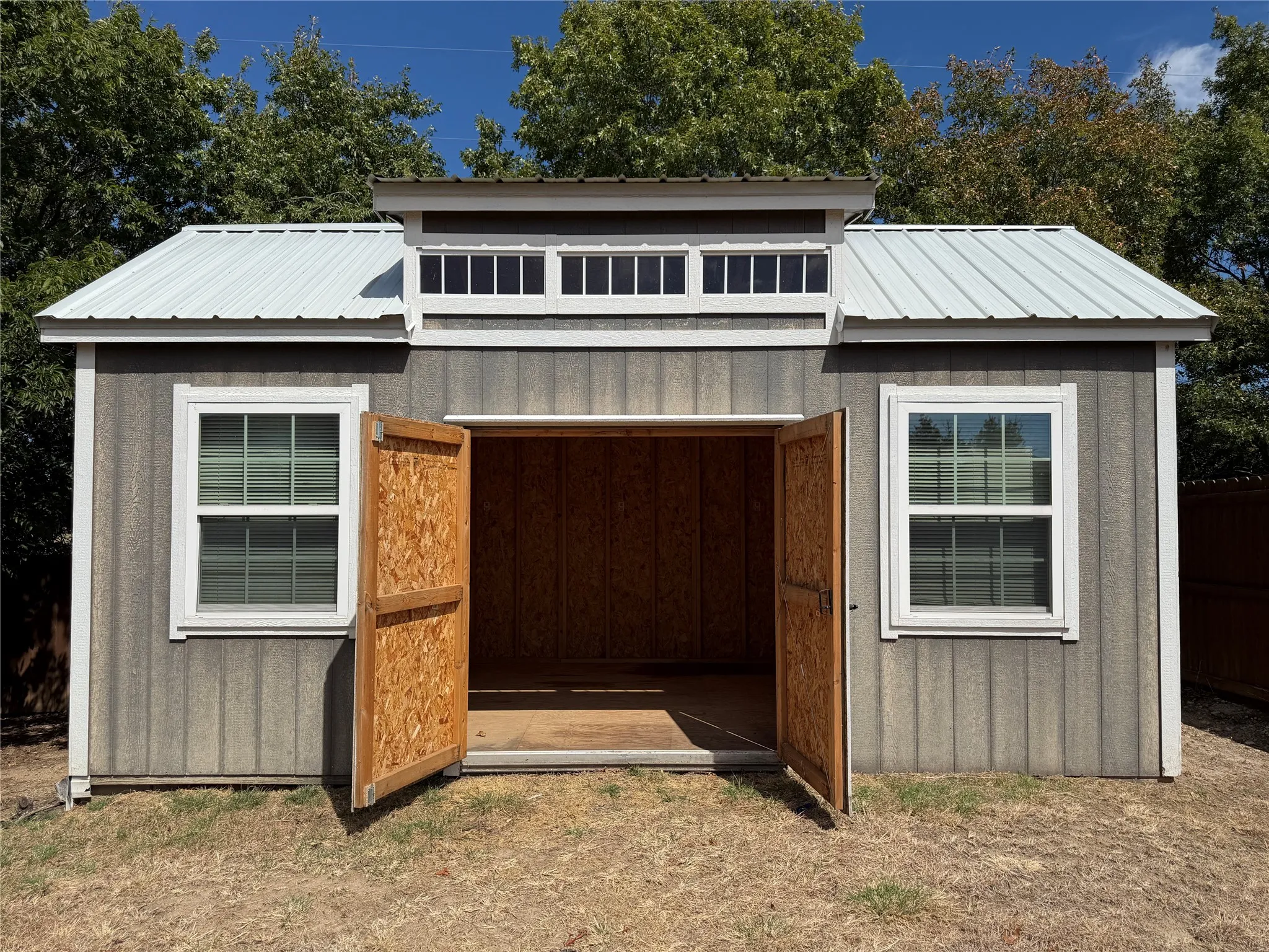 Wood-finish siding, white window trim, metal roof, and clerestory windows