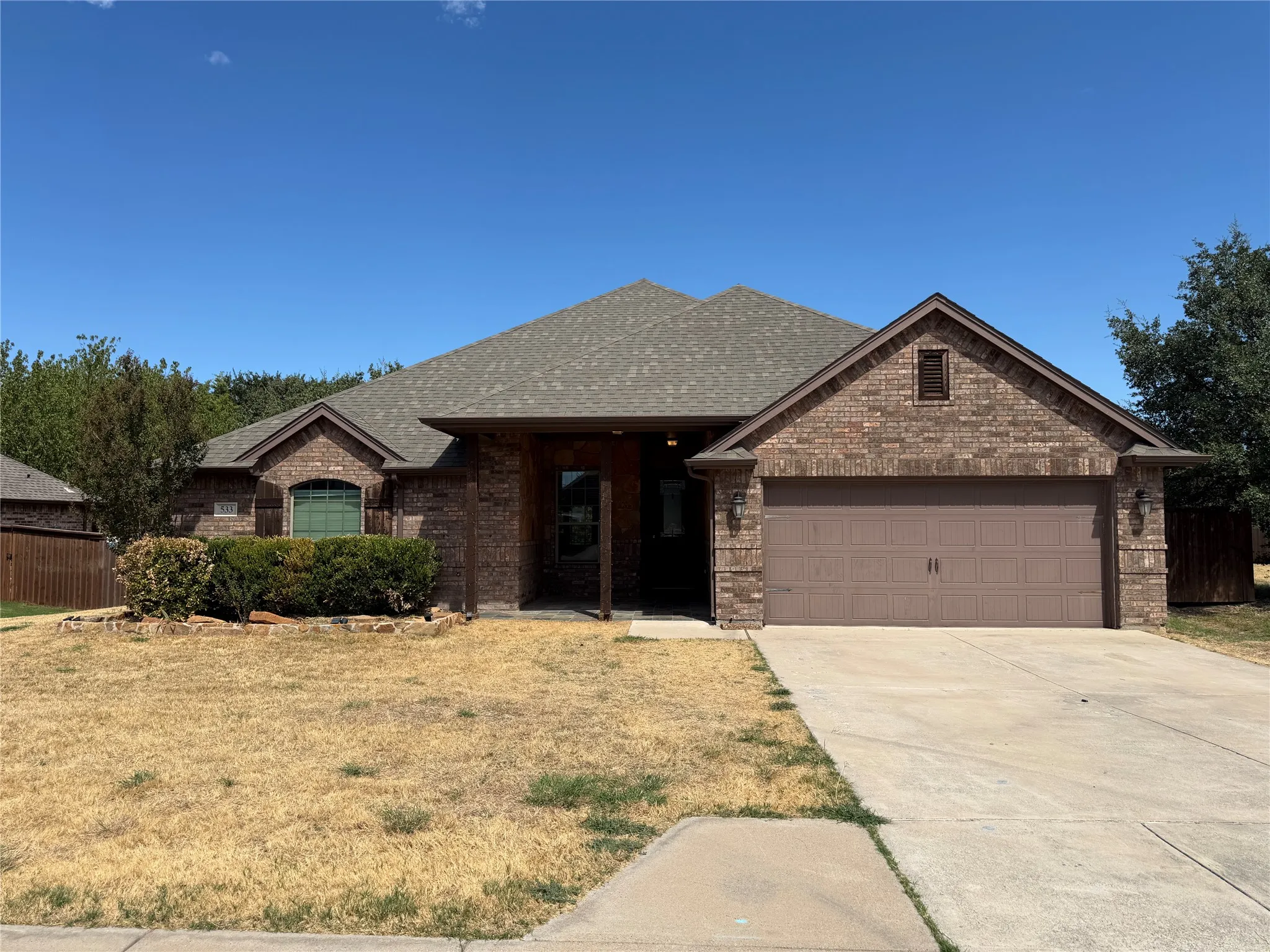 Brick exterior with a shingled roof, an attached two-car garage, and a concrete driveway