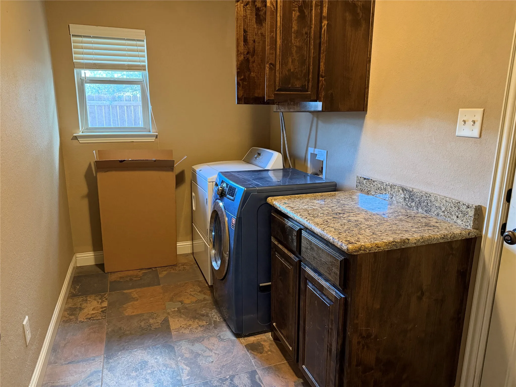 Built-in cabinetry with a stone-finish countertop, coordinating overhead cabinet, and tile flooring
