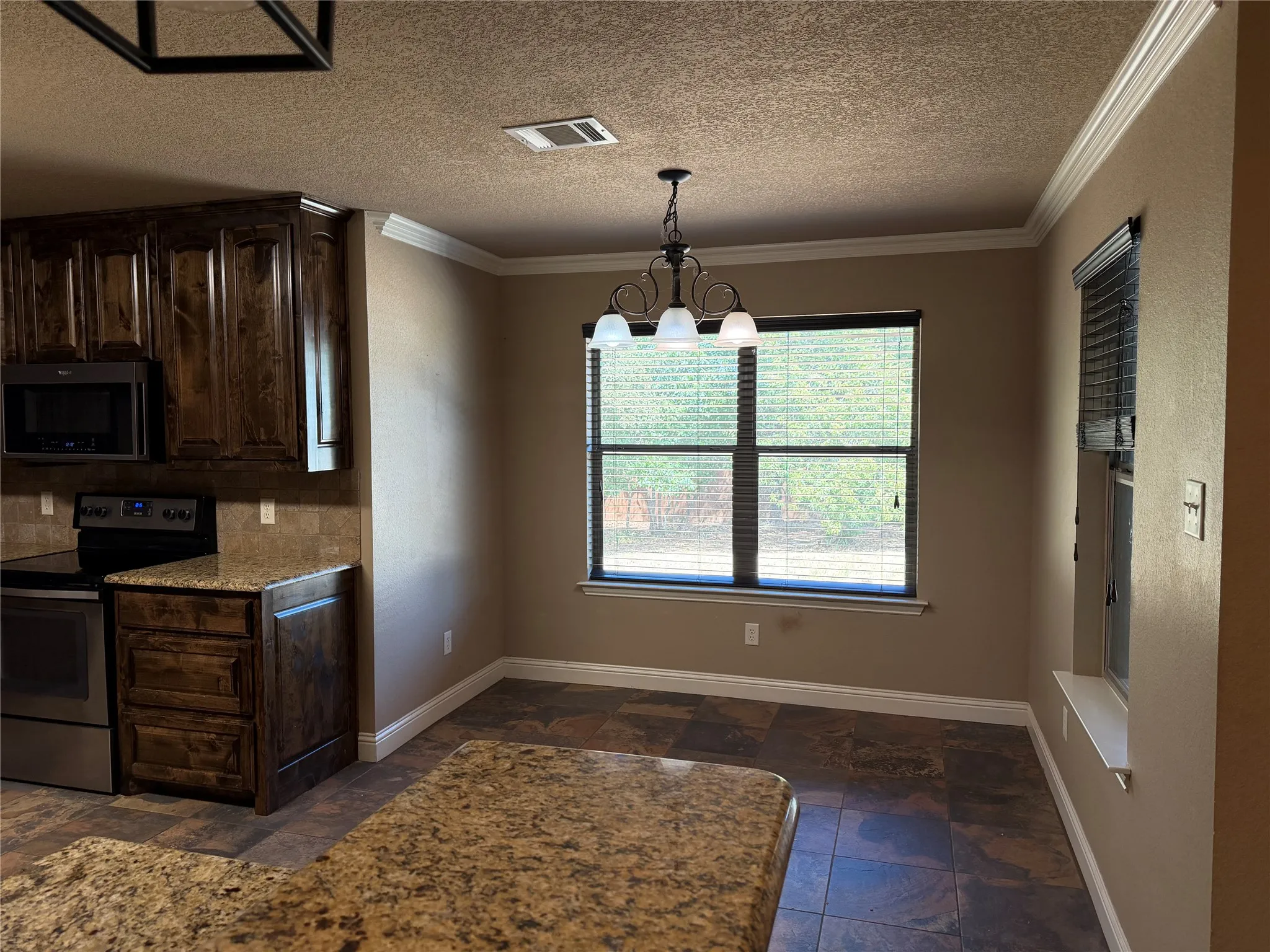 Kitchen with dark wood cabinetry, stainless steel appliances, stone countertops, and tile flooring