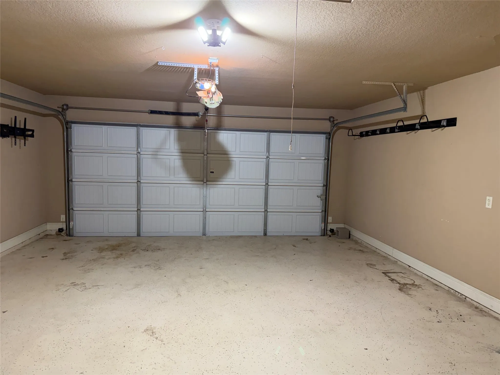 Attached garage with a panel-style door, overhead lighting, and wall-mounted storage solutions