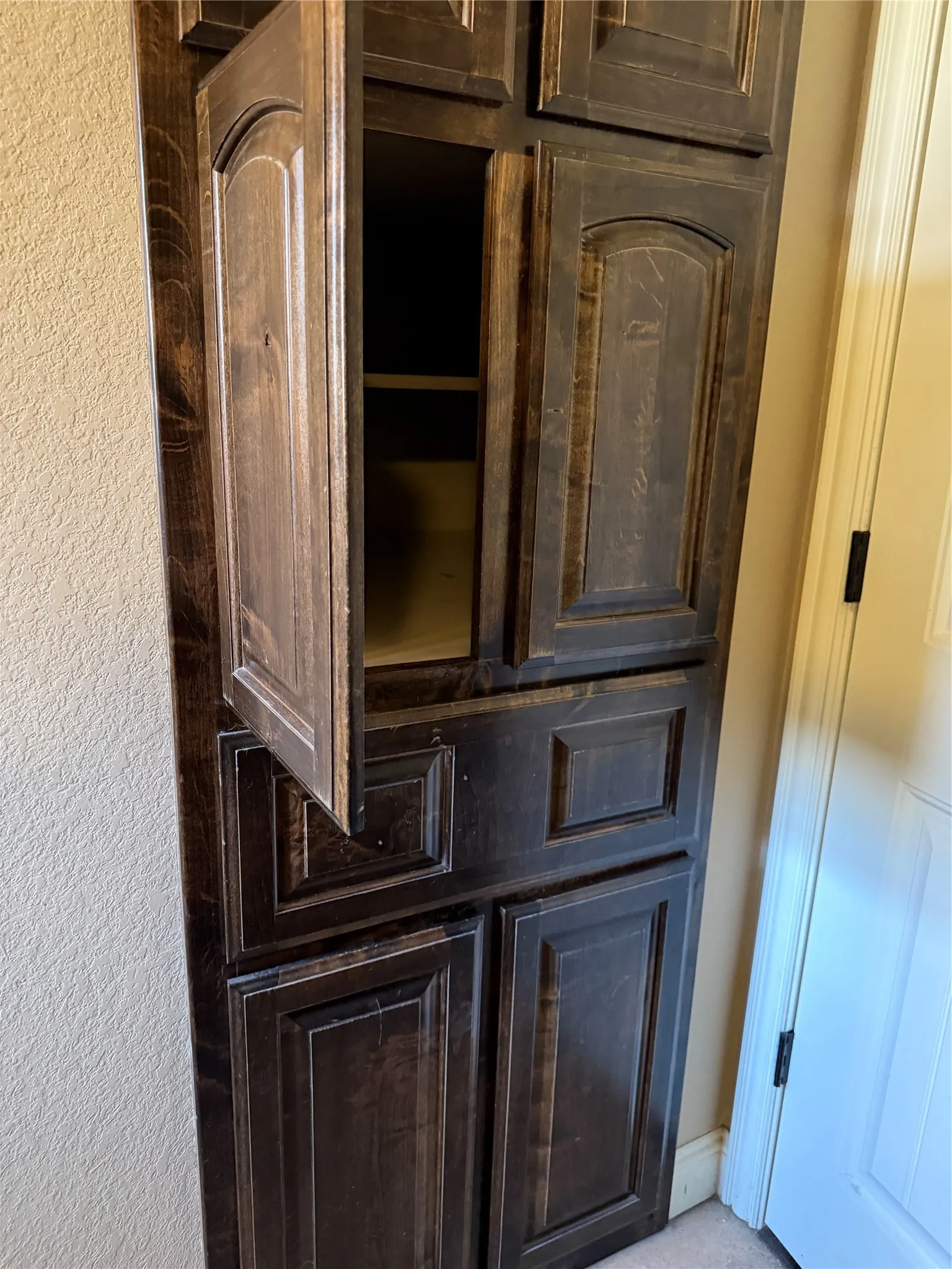 Built-in storage cabinetry featuring wood-finish doors with raised panels and concealed hinges
