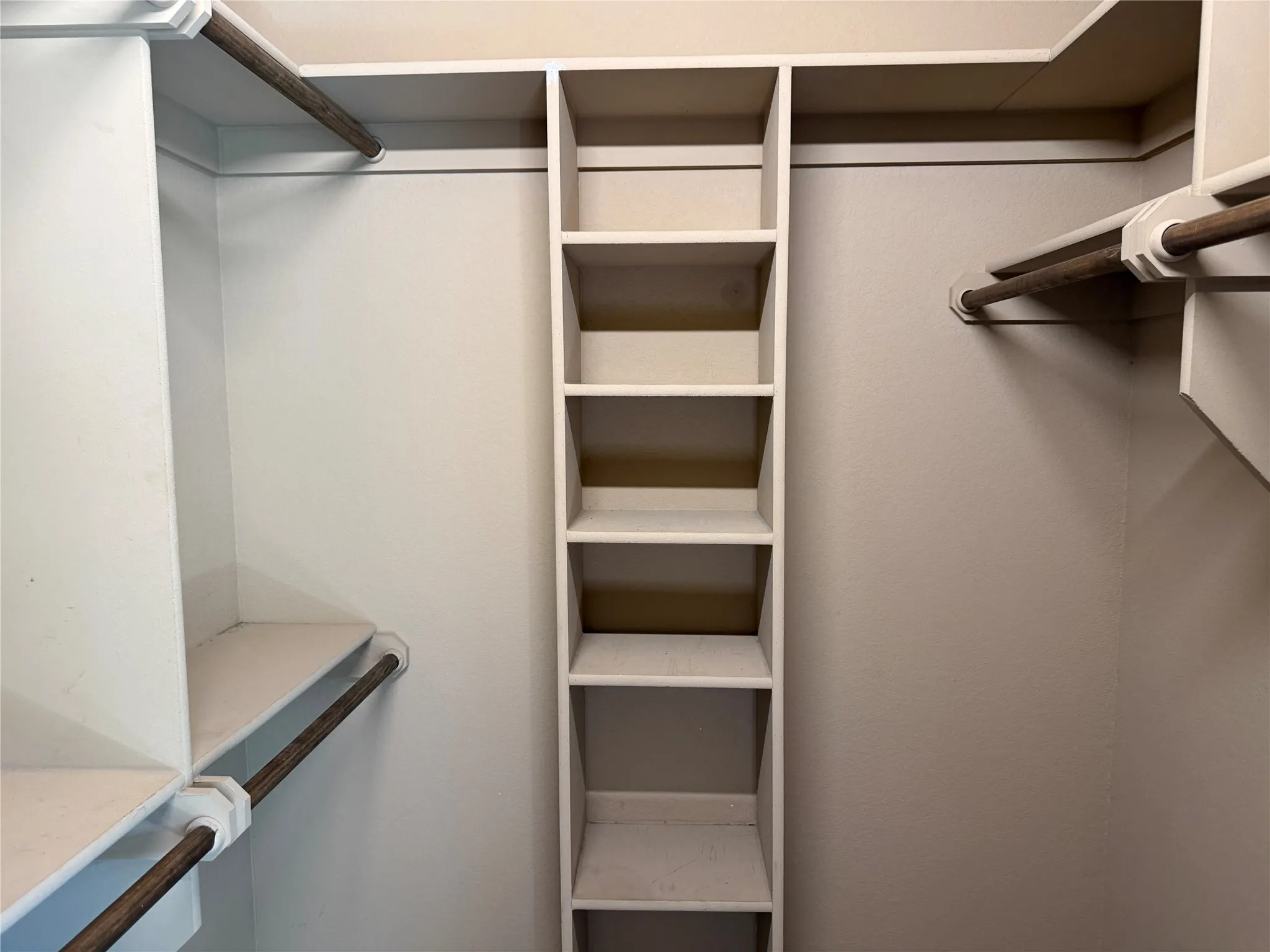 Built-in closet shelving, multiple hanging rods, and integrated storage compartments