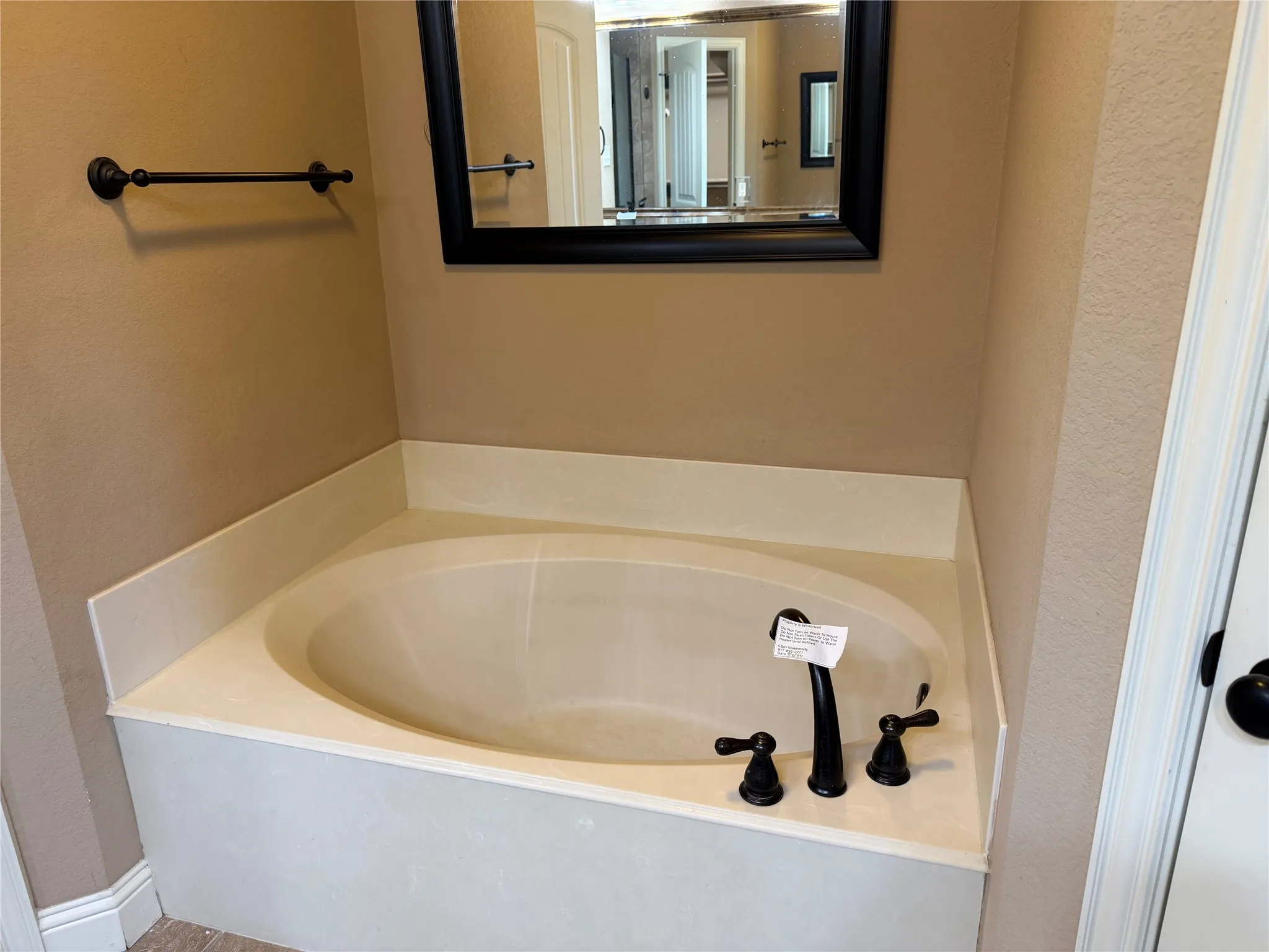 Built-in soaking tub with a deck surround, featuring a matte black faucet and handles