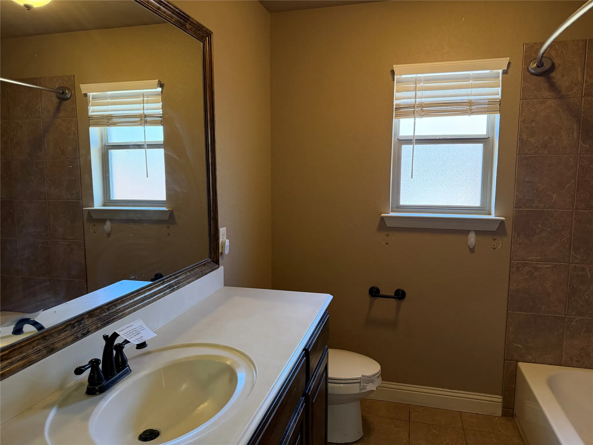 Vanity with an integrated sink, bronze-finish faucet, and a large framed mirror