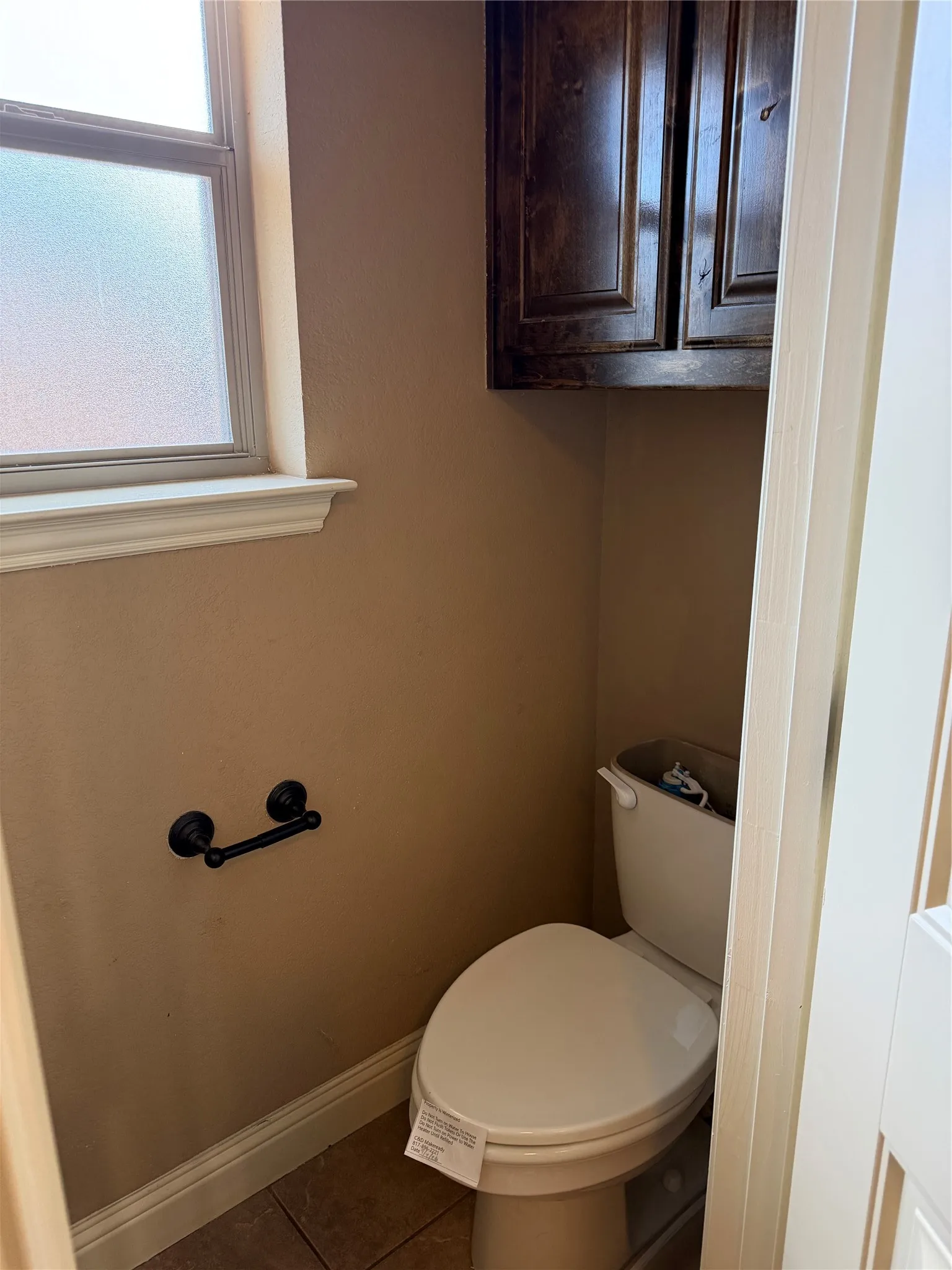 Frosted window, dark wood-finish cabinetry, tile flooring, and white trim