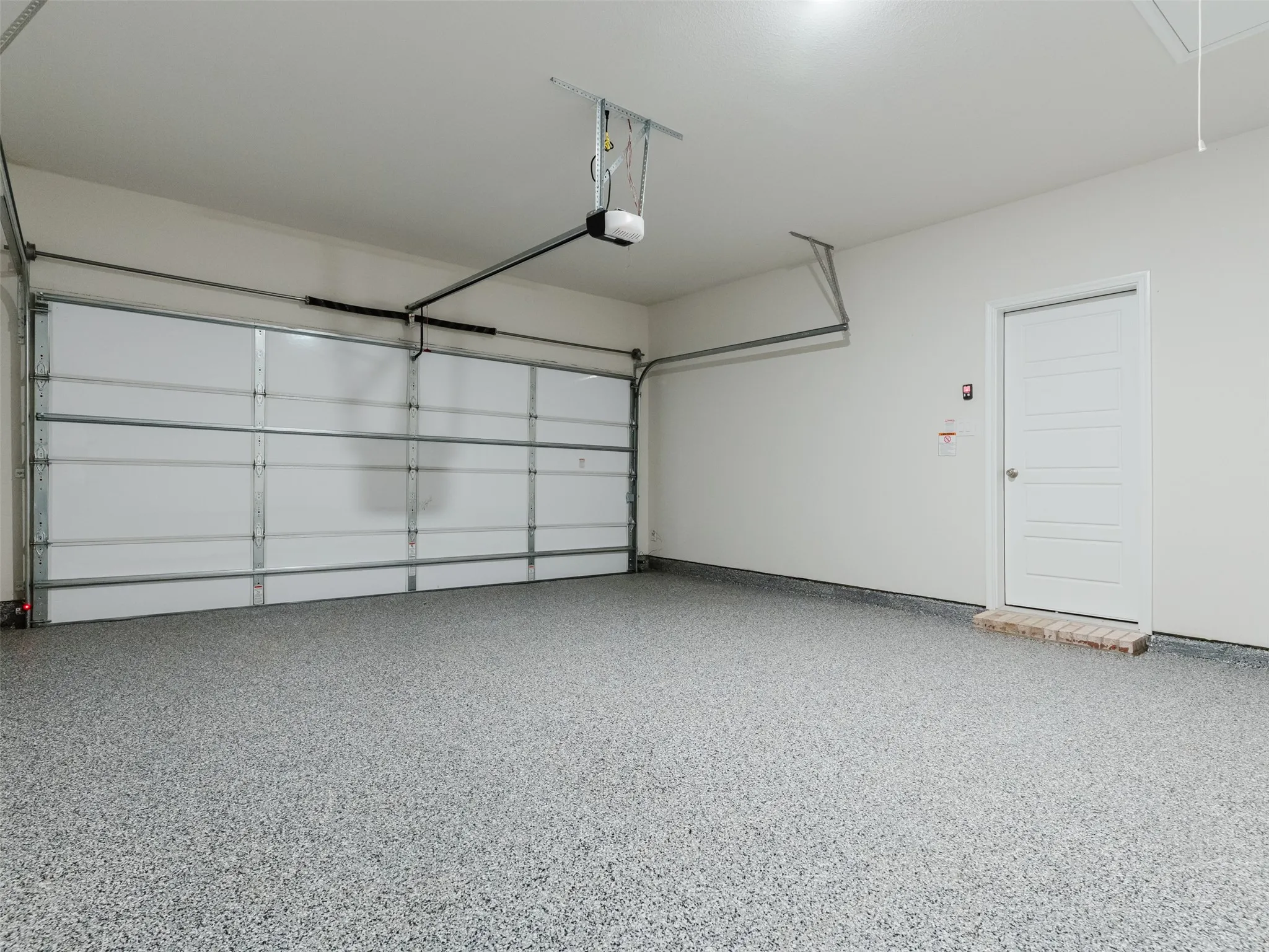 Garage with speckled gray epoxy flooring and an automatic garage door opener