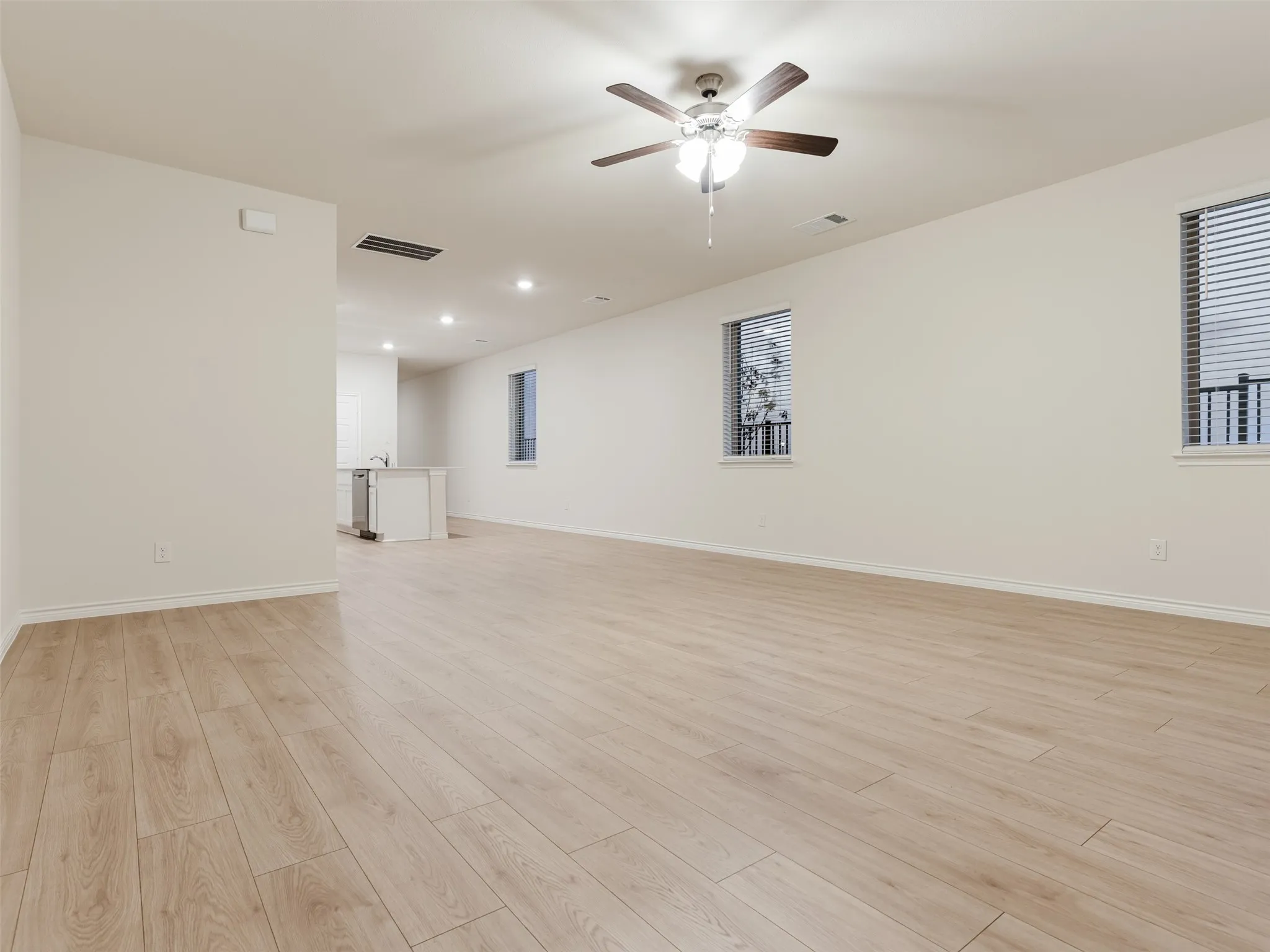 Spacious room with wood-finish flooring, recessed lighting, and a ceiling fan