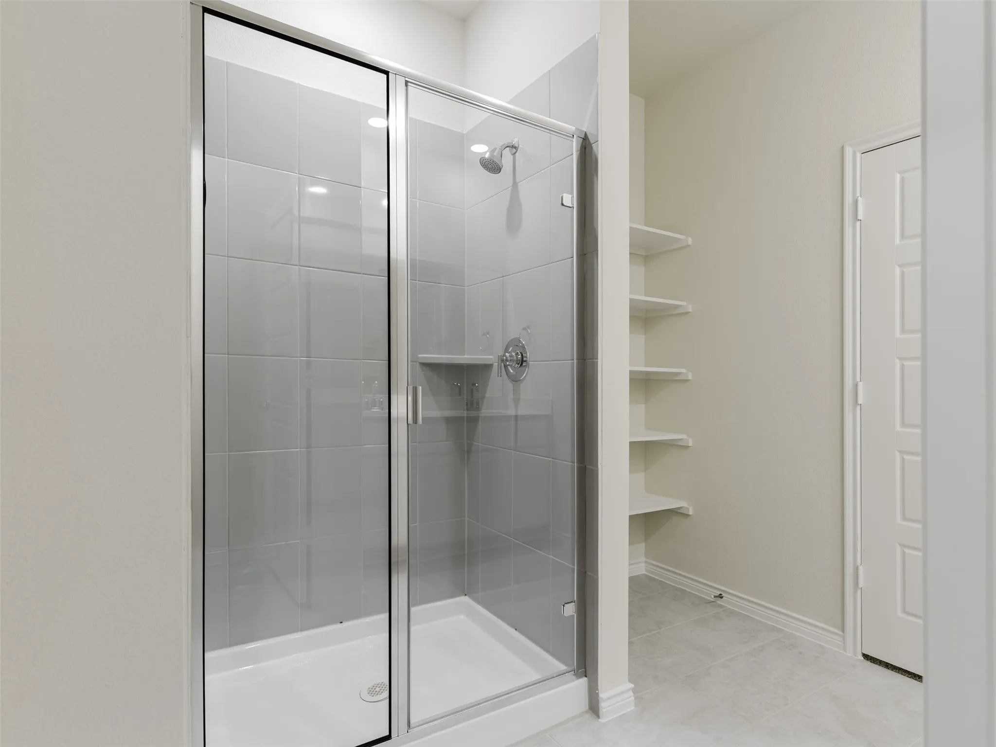 Glass-enclosed shower with a tiled interior, chrome fixtures, and a built-in shower niche