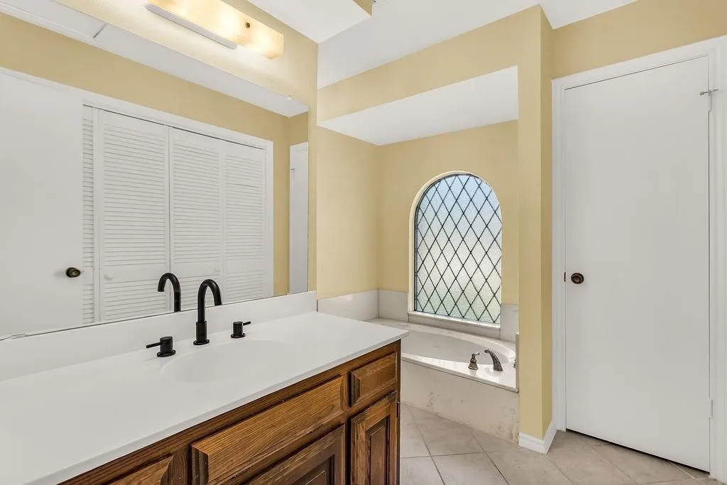 Built-in vanity with wood cabinetry, white countertop, and dual sinks with matte black fixtures
