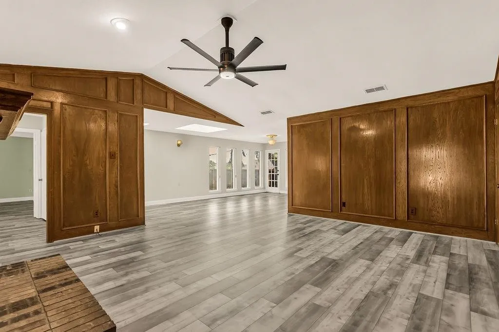 Wood-paneled wall accents, vaulted ceiling, contemporary ceiling fan, recessed lighting, and light wood-finish flooring