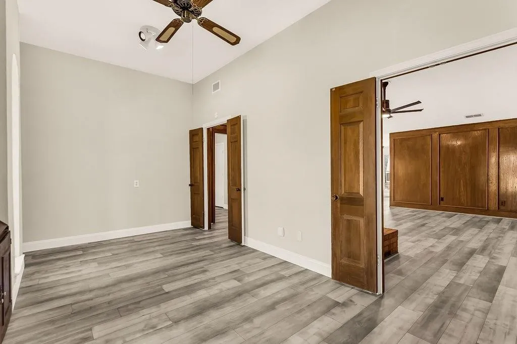 Wood-finish flooring throughout, vaulted ceiling with a ceiling fan, and solid wood doors