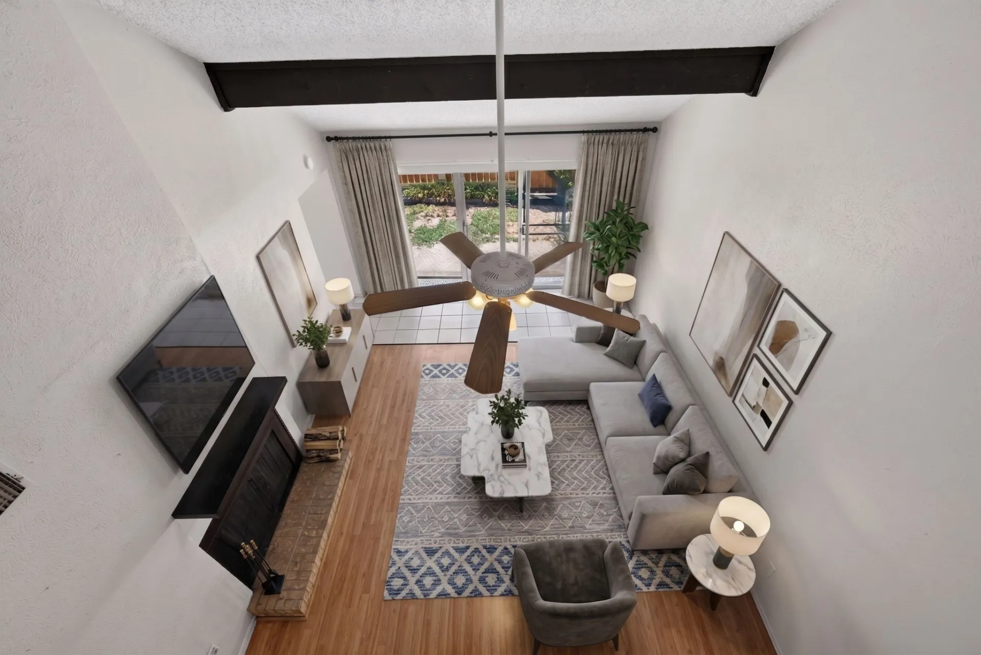 Vaulted ceiling with exposed beam, wood-finish flooring, brick fireplace, and sliding glass door