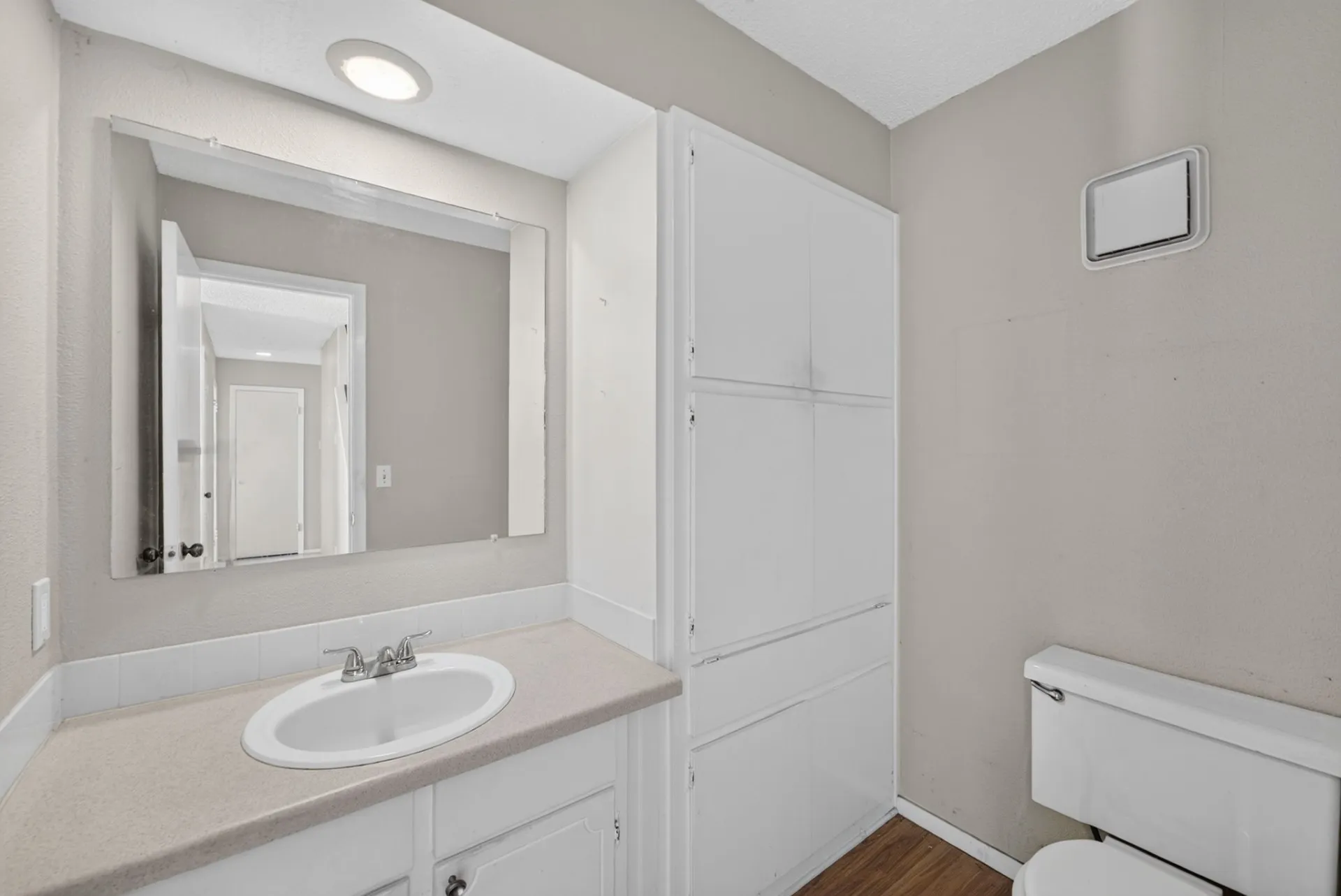 Vanity with integrated sink, chrome faucet, and expansive mirror