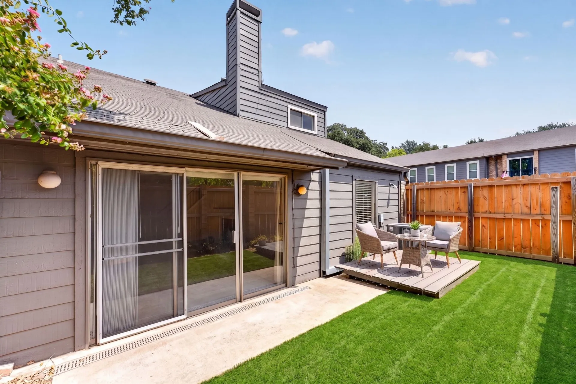 Private outdoor space featuring a wood fence, artificial turf, and a raised wood patio