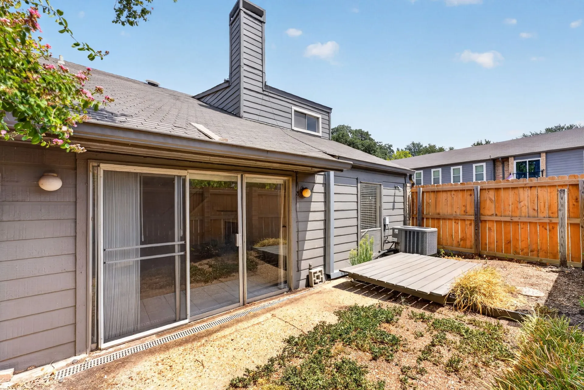 Rear patio with sliding glass doors, wooden decking, and a privacy fence