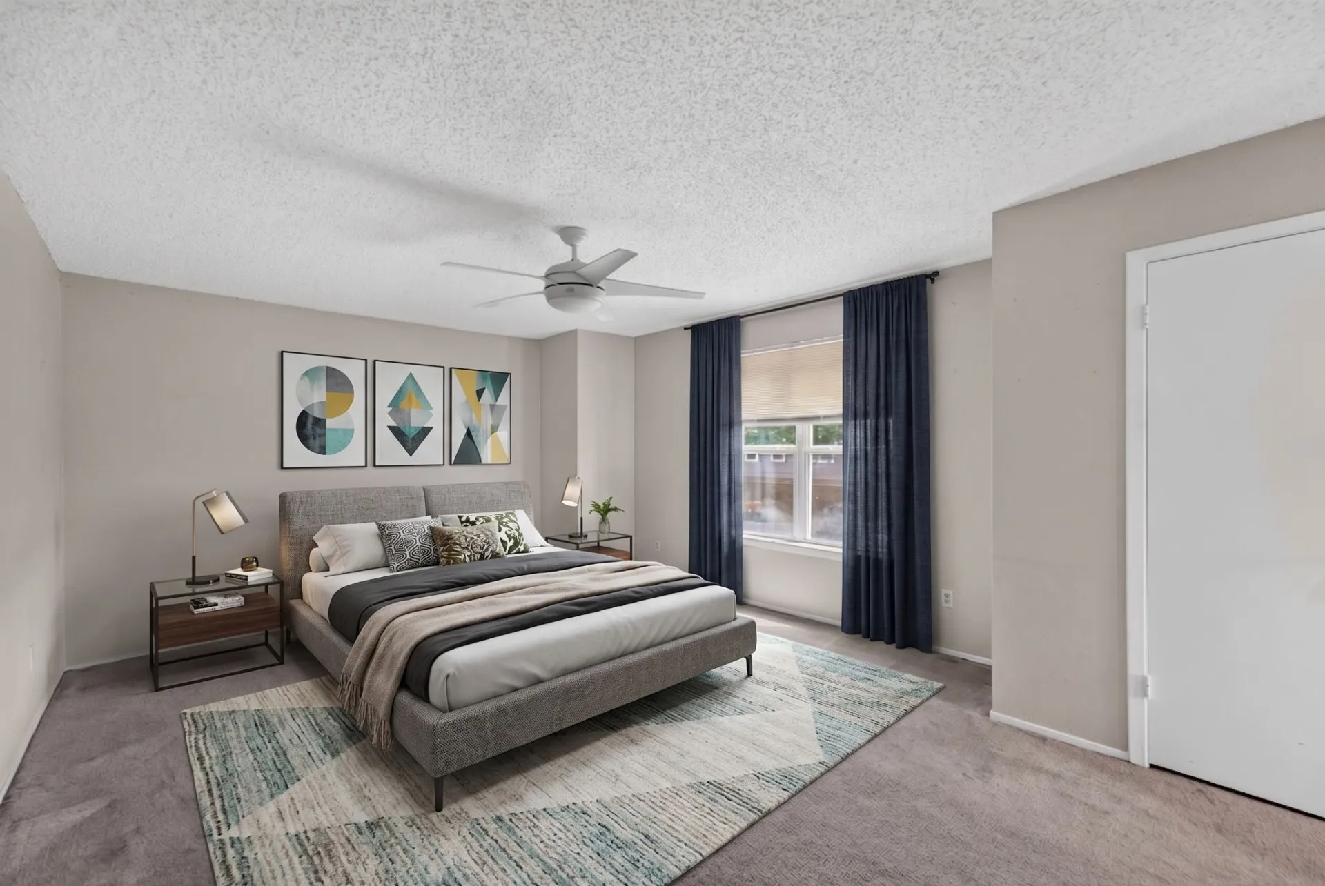 Neutral wall paint, ceiling fan, window with roller shade, and carpeted flooring