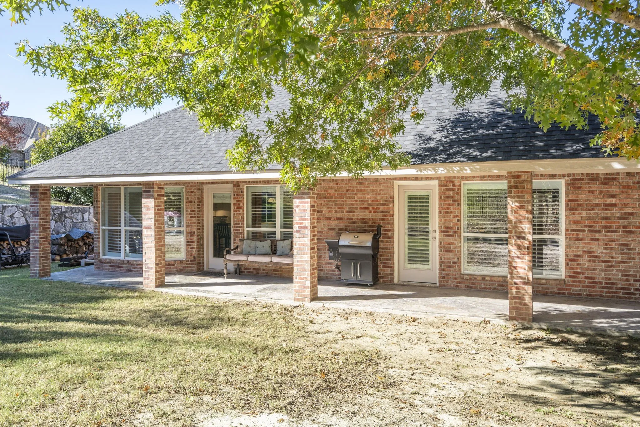 Expansive brick exterior with a covered patio, multiple windows with blinds, and direct outdoor access