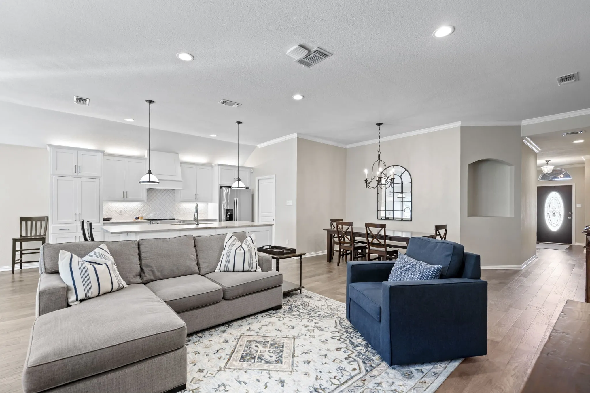 Expansive open-concept living space with wood-finish flooring, recessed lighting, and crown molding