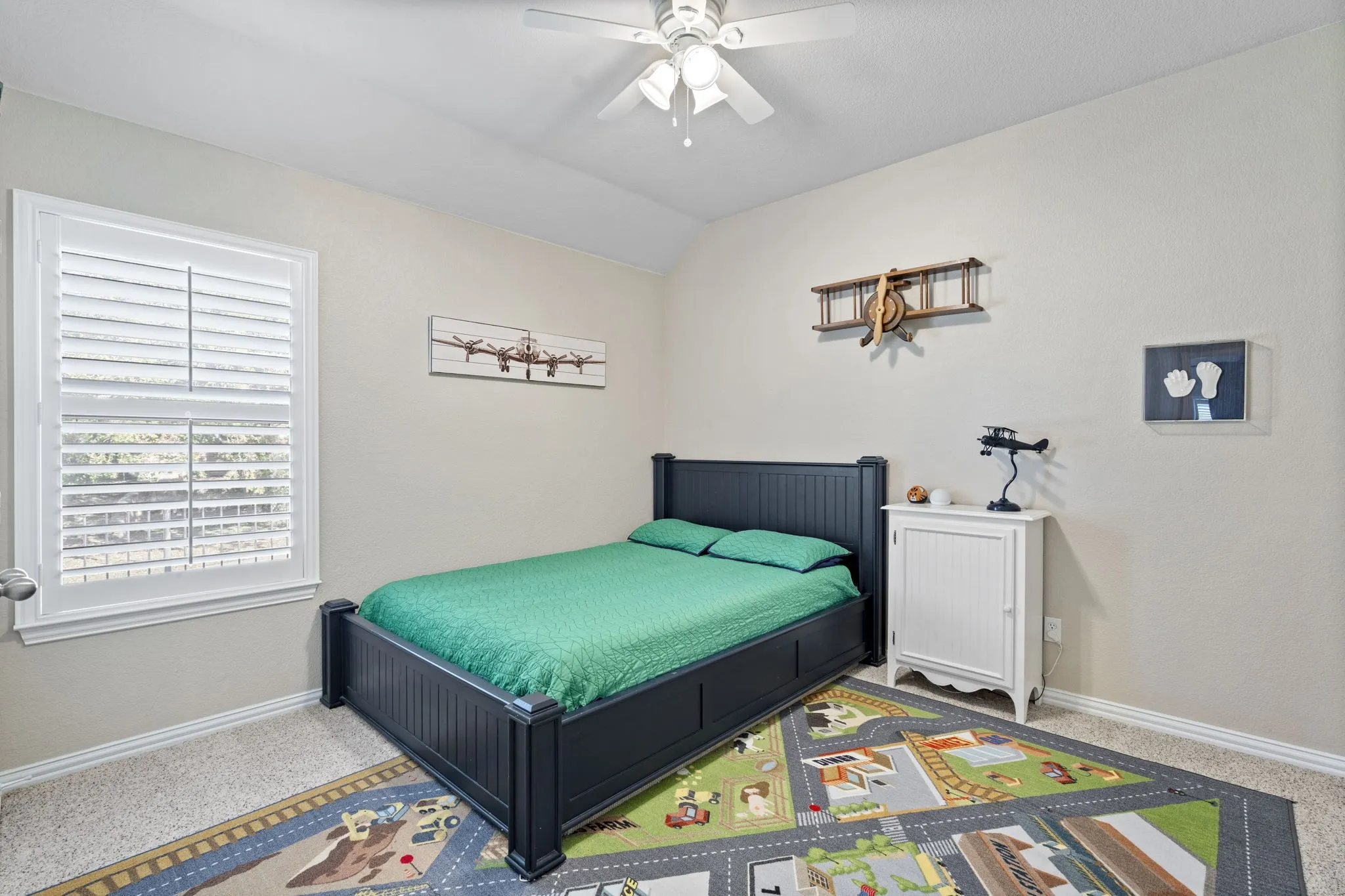 Textured walls, ceiling fan, window with plantation shutters, carpeting, and crown molding