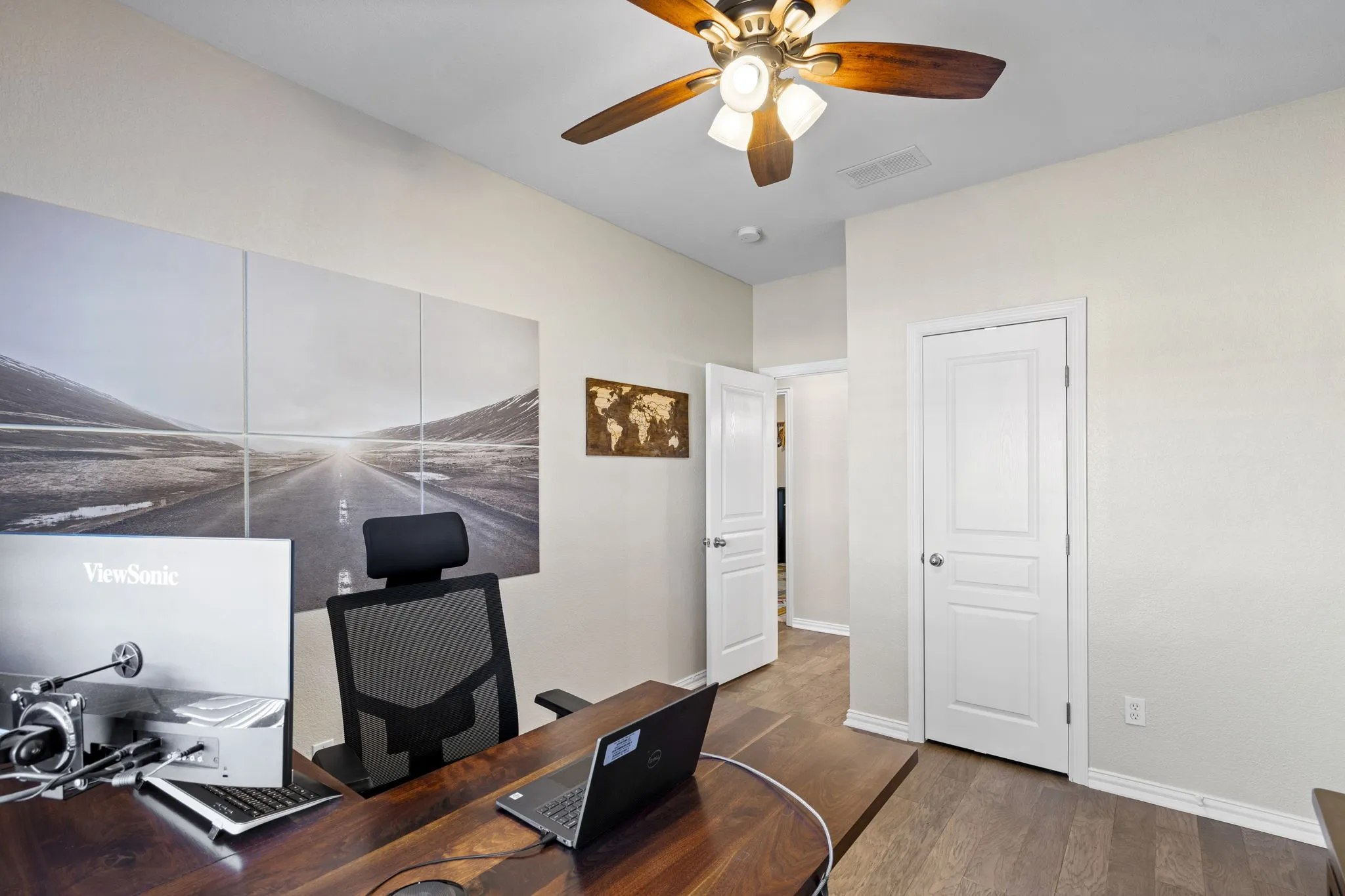 Wood-finish flooring, two paneled doors, and a ceiling fan with integrated lighting