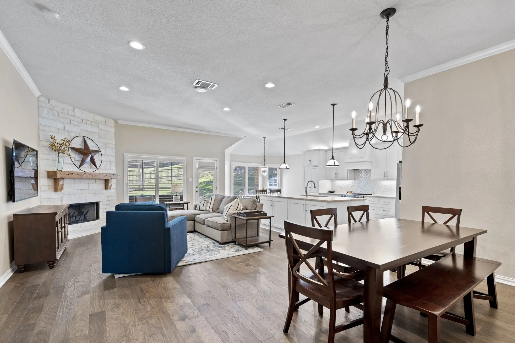 Spacious living area with wood-finish flooring, a stone-accented fireplace, and a large kitchen island