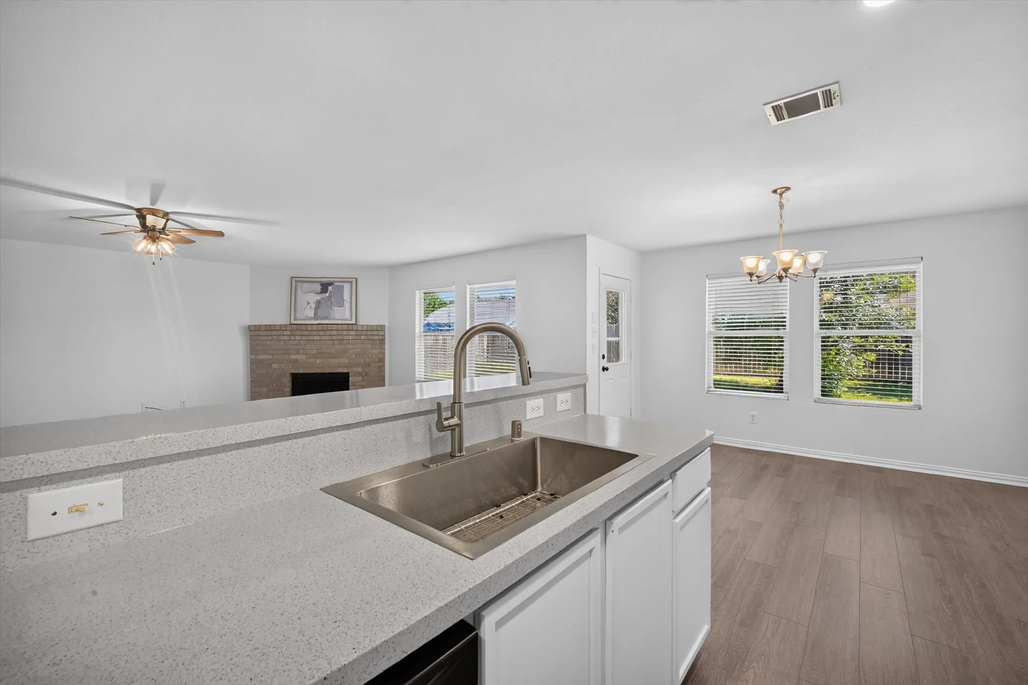 Kitchen island with an undermount sink and brushed nickel faucet, light-toned countertops, and white cabinetry