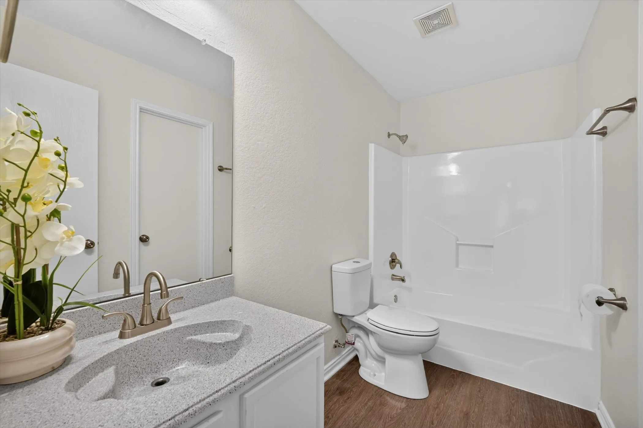 Bathroom featuring a single vanity with an integrated sink, brushed nickel faucet, a frameless mirror, and a shower/tub combination