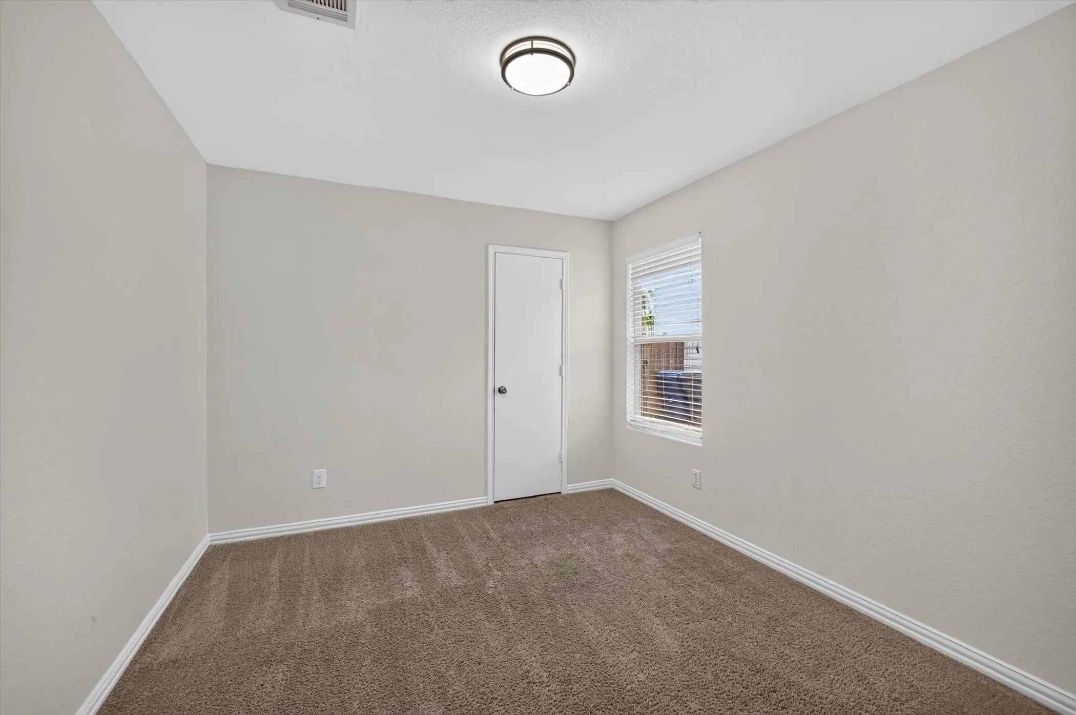 Carpeted flooring, neutral wall tones, window with horizontal blinds, flush mount ceiling light, and white interior door