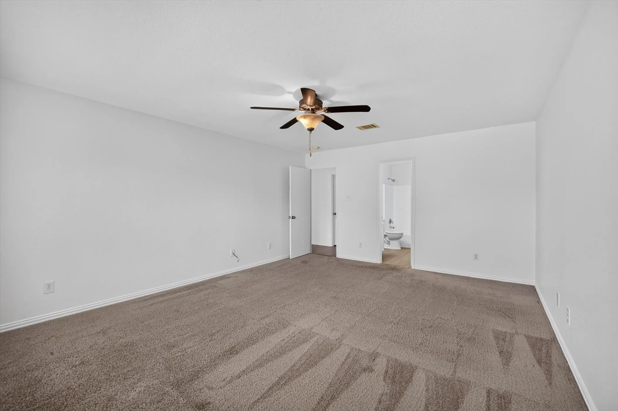 Spacious room with carpet flooring, a ceiling fan, and white walls