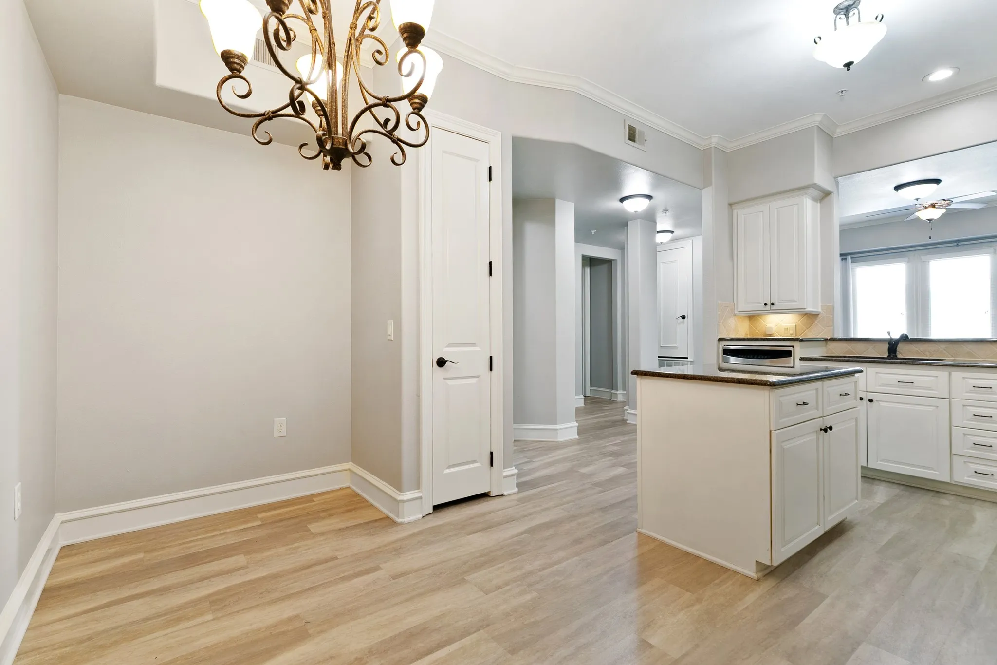 Open-concept living space, a kitchen island with storage, white cabinetry, and a decorative chandelier with space for a kitchen table