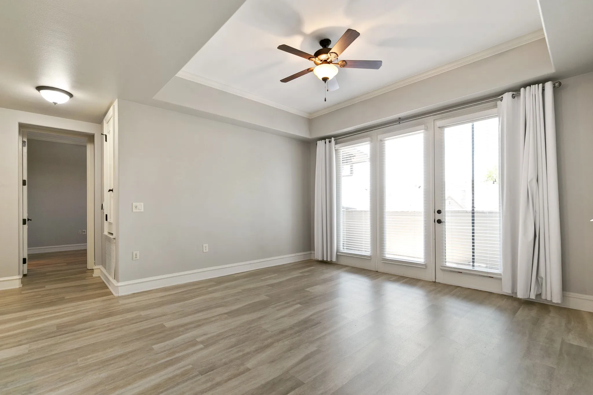 Tray ceiling, ceiling fan with integrated lighting, recessed lighting, and white trim. Door opens to the patio