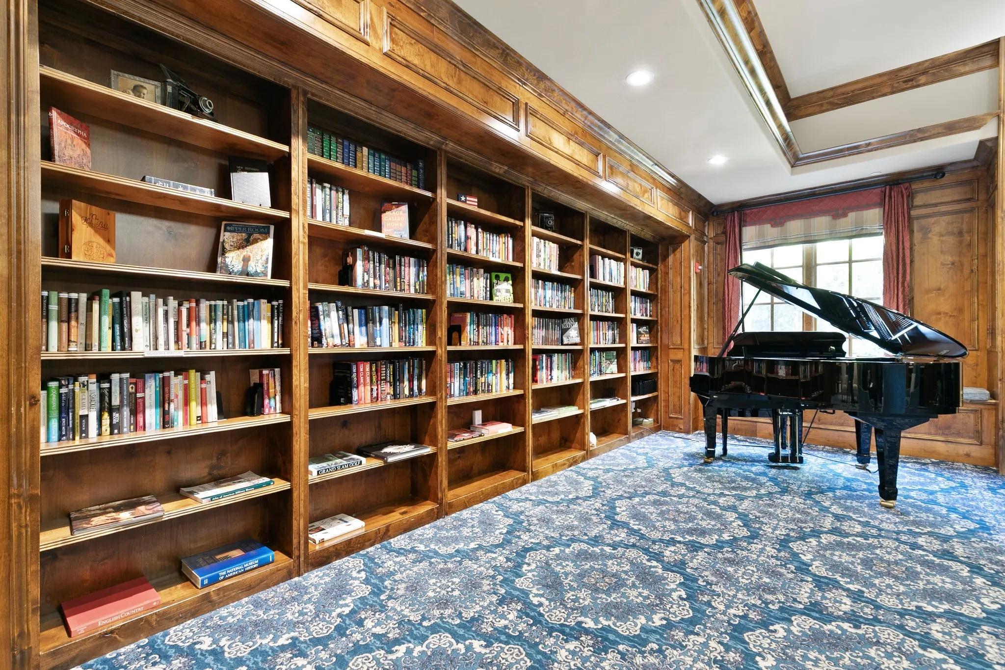 Extensive built-in wood shelving units, wood-paneled walls, patterned carpeting, and recessed lighting