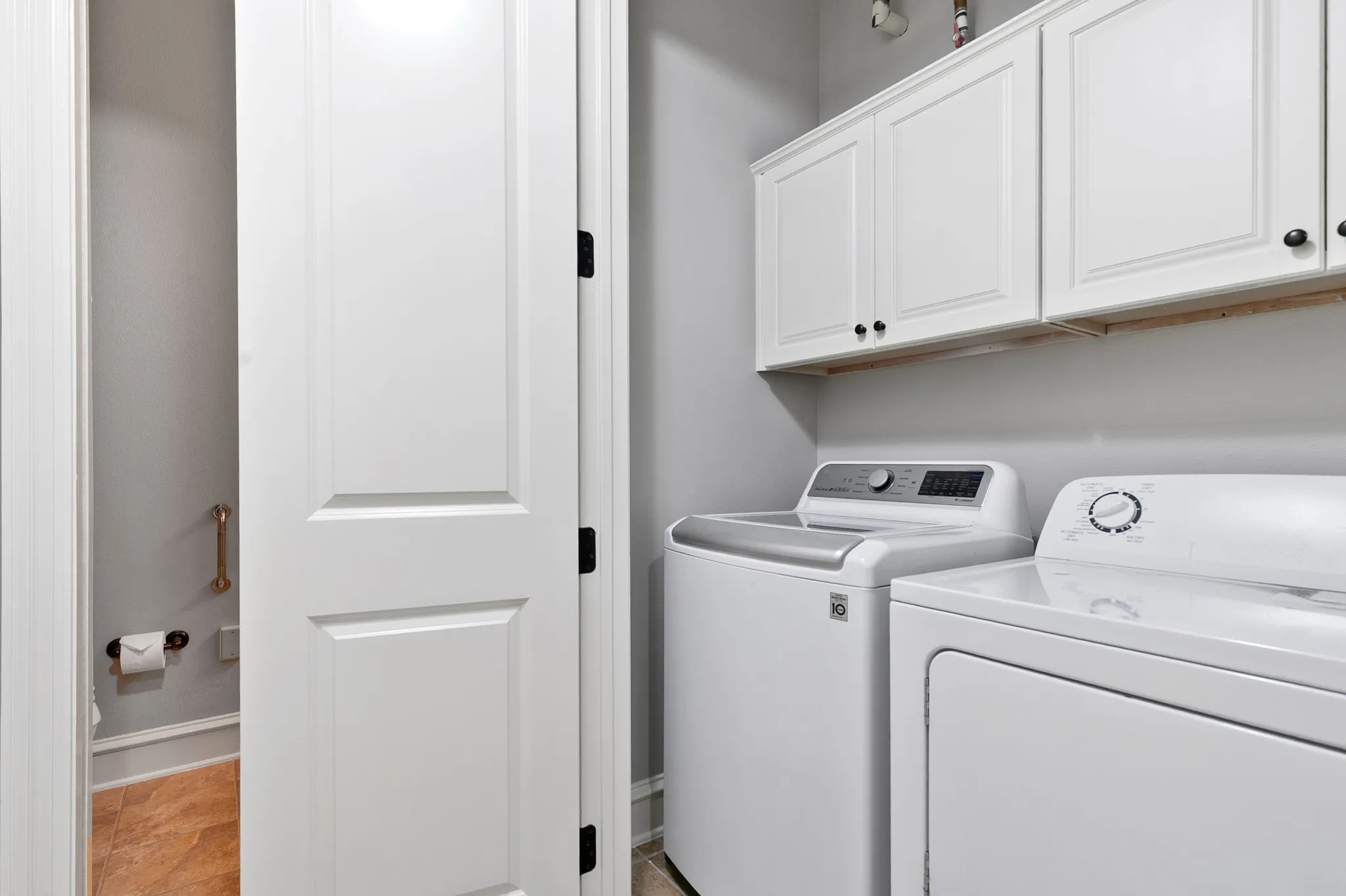 White paneled doors with black hardware, white upper cabinetry with black hardware, and tiled flooring