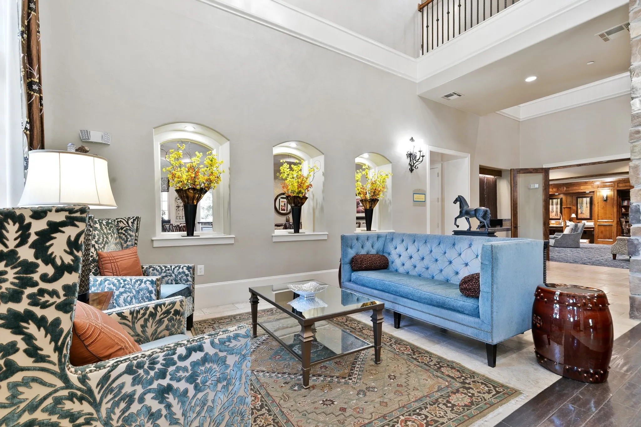 Two-story ceiling, arched window features, crown molding, stone accent wall, and wood-finish flooring