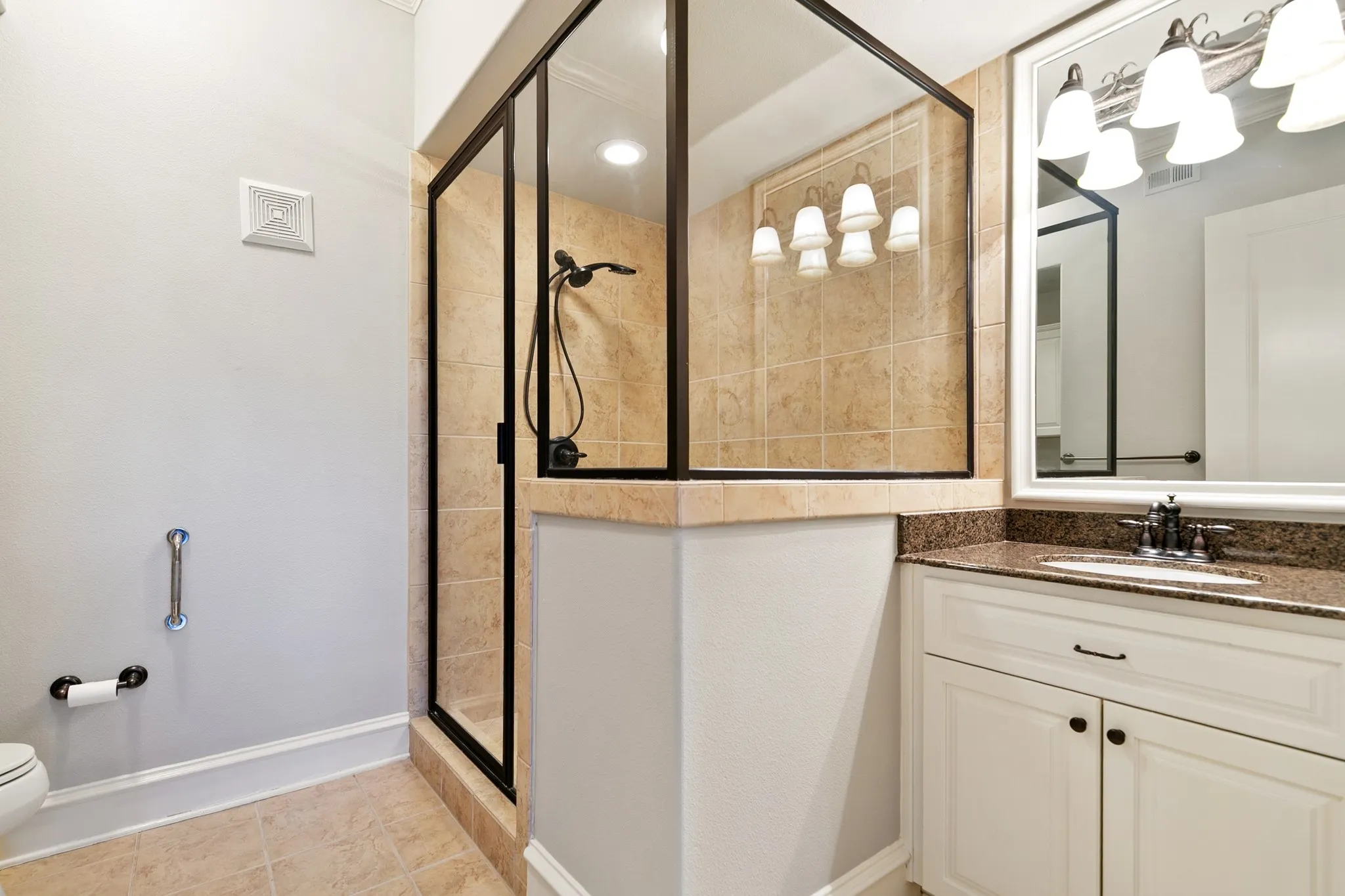 Frameless glass shower enclosure with a dark bronze frame, tiled shower surround, and a dark bronze shower fixture