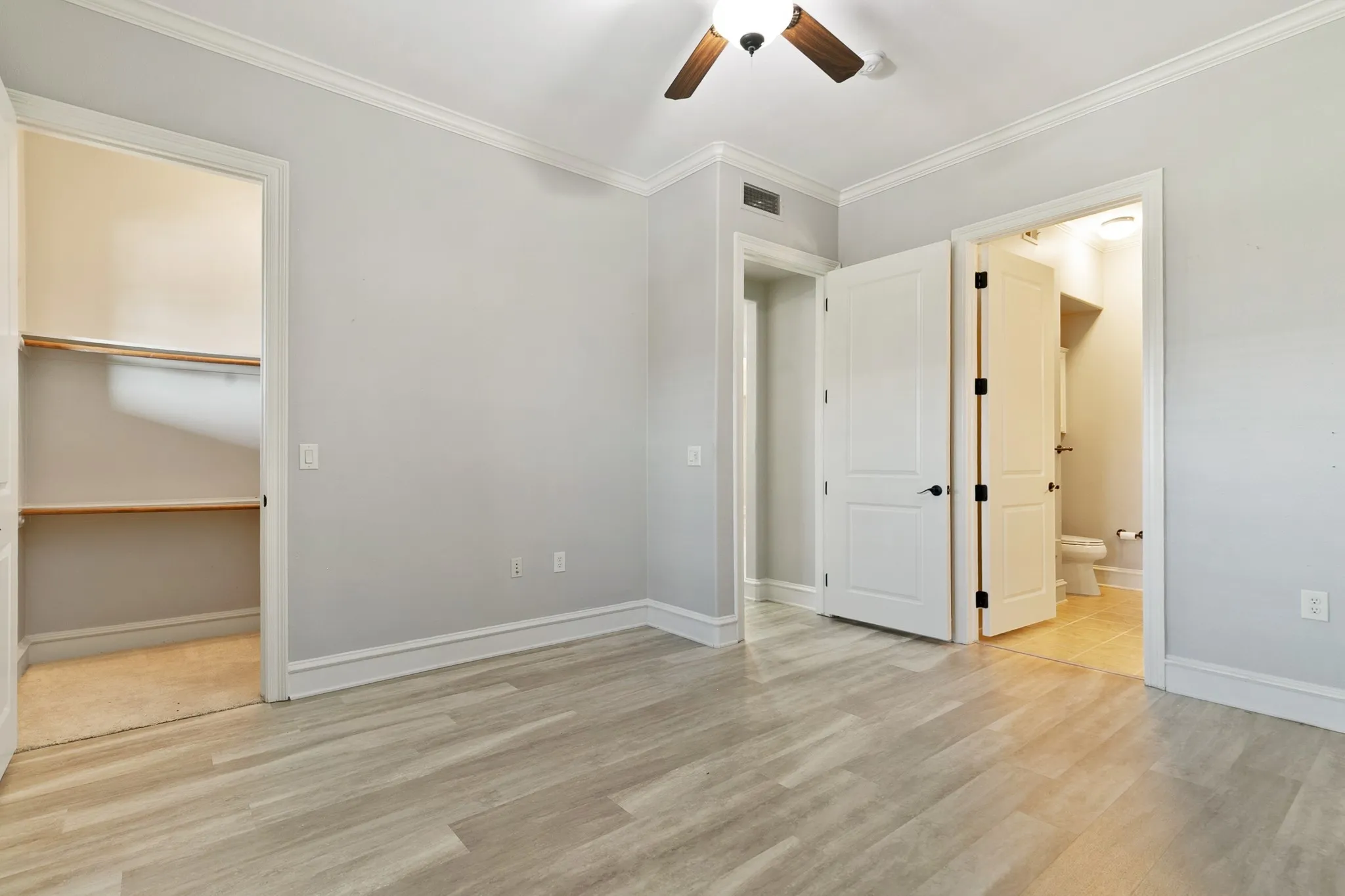 Secondary Bedroom with crown molding, ceiling fan, built-in closet shelving, and a panel door