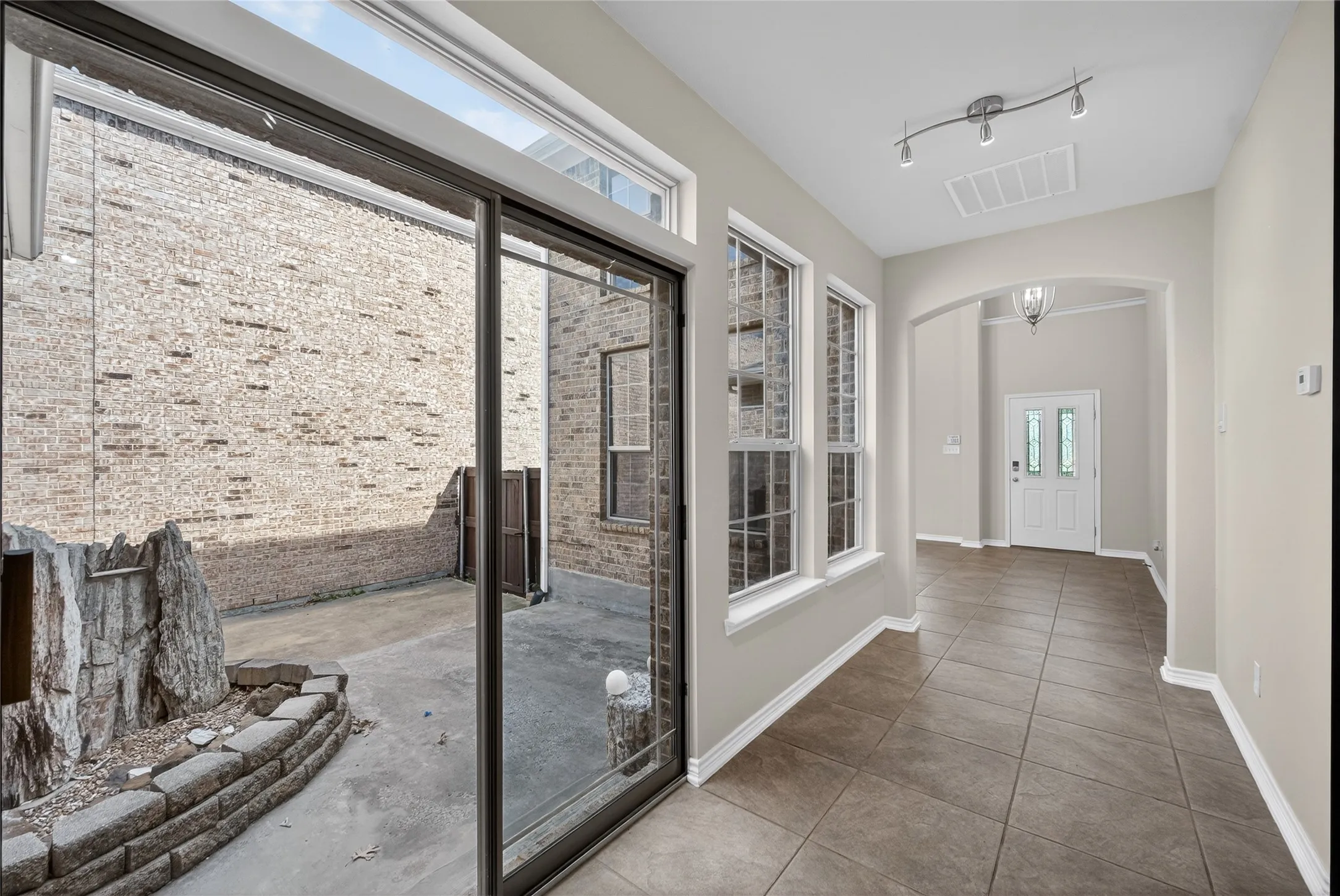 Sliding glass door access to an outdoor patio with brick veneer walls and a rock feature