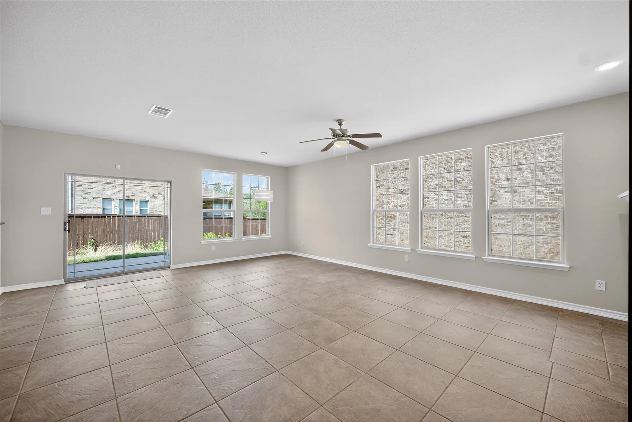 Spacious living area featuring neutral wall tones, tile flooring, and multiple windows