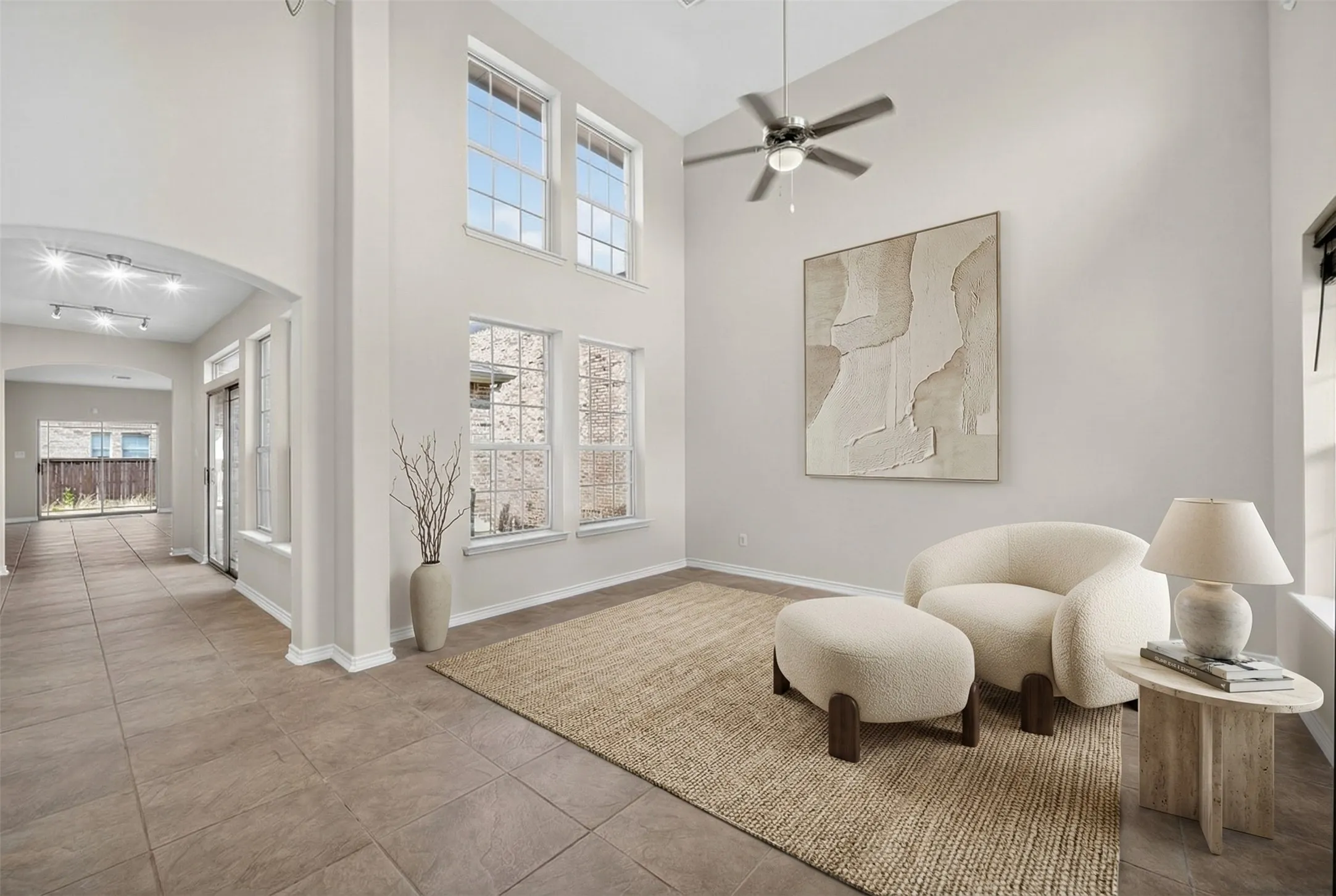 Soaring ceilings with a ceiling fan, arched doorways, multiple large windows, and tile flooring