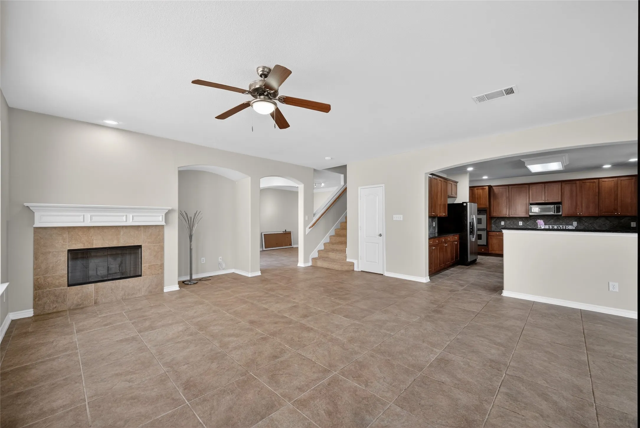 Spacious interior featuring tile flooring, a fireplace with a white mantel, and an arched entryway