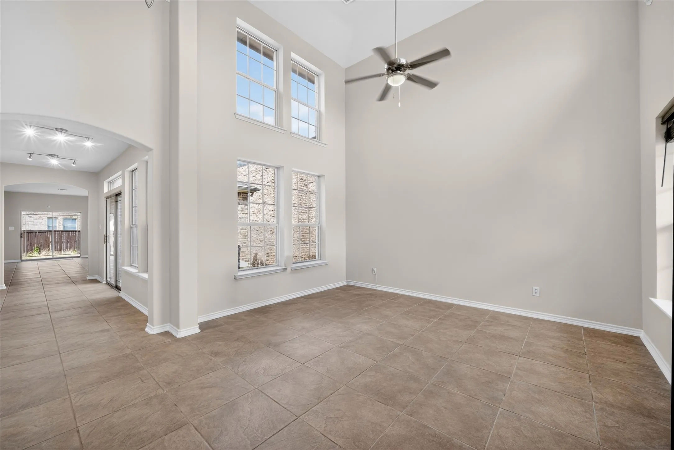Soaring vaulted ceiling, ceiling fan, large format tile flooring, multiple windows, and recessed lighting