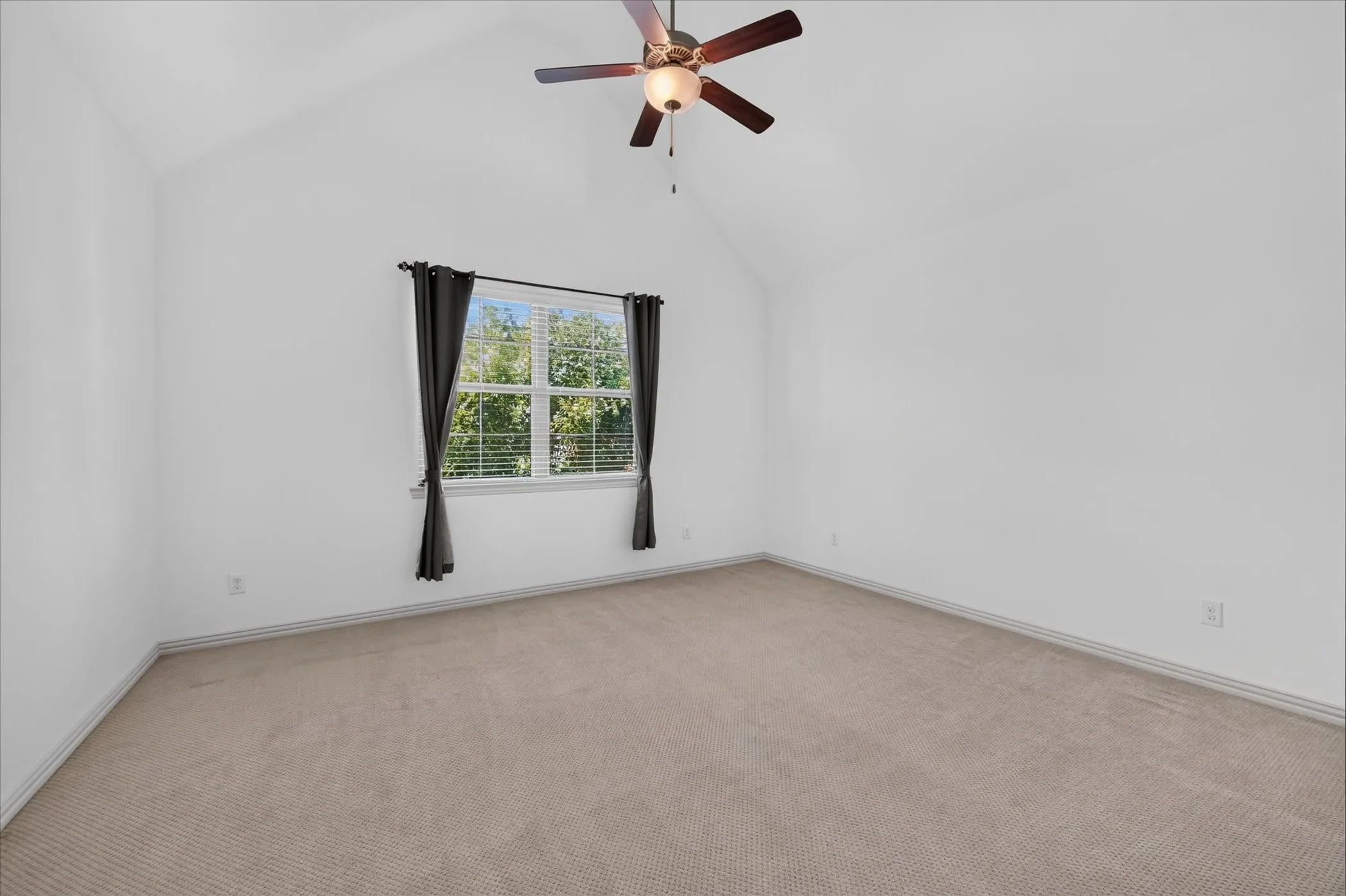 Vaulted ceiling, ceiling fan, window with blinds, and neutral carpet