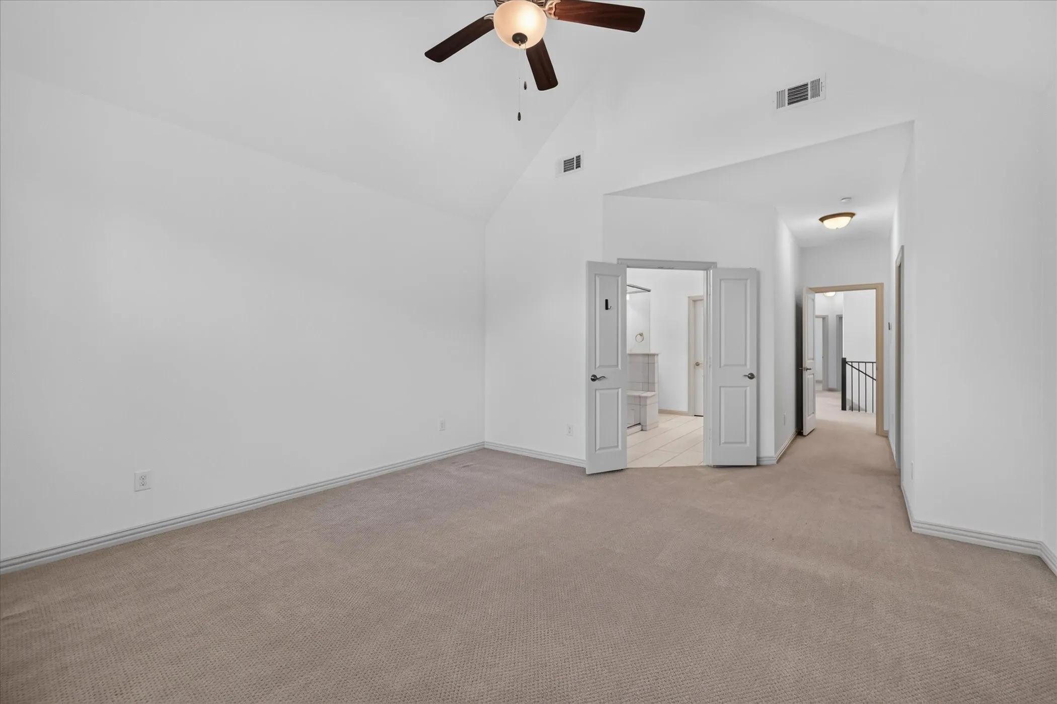 Vaulted ceiling, ceiling fan, neutral carpet flooring, double French doors, and recessed lighting