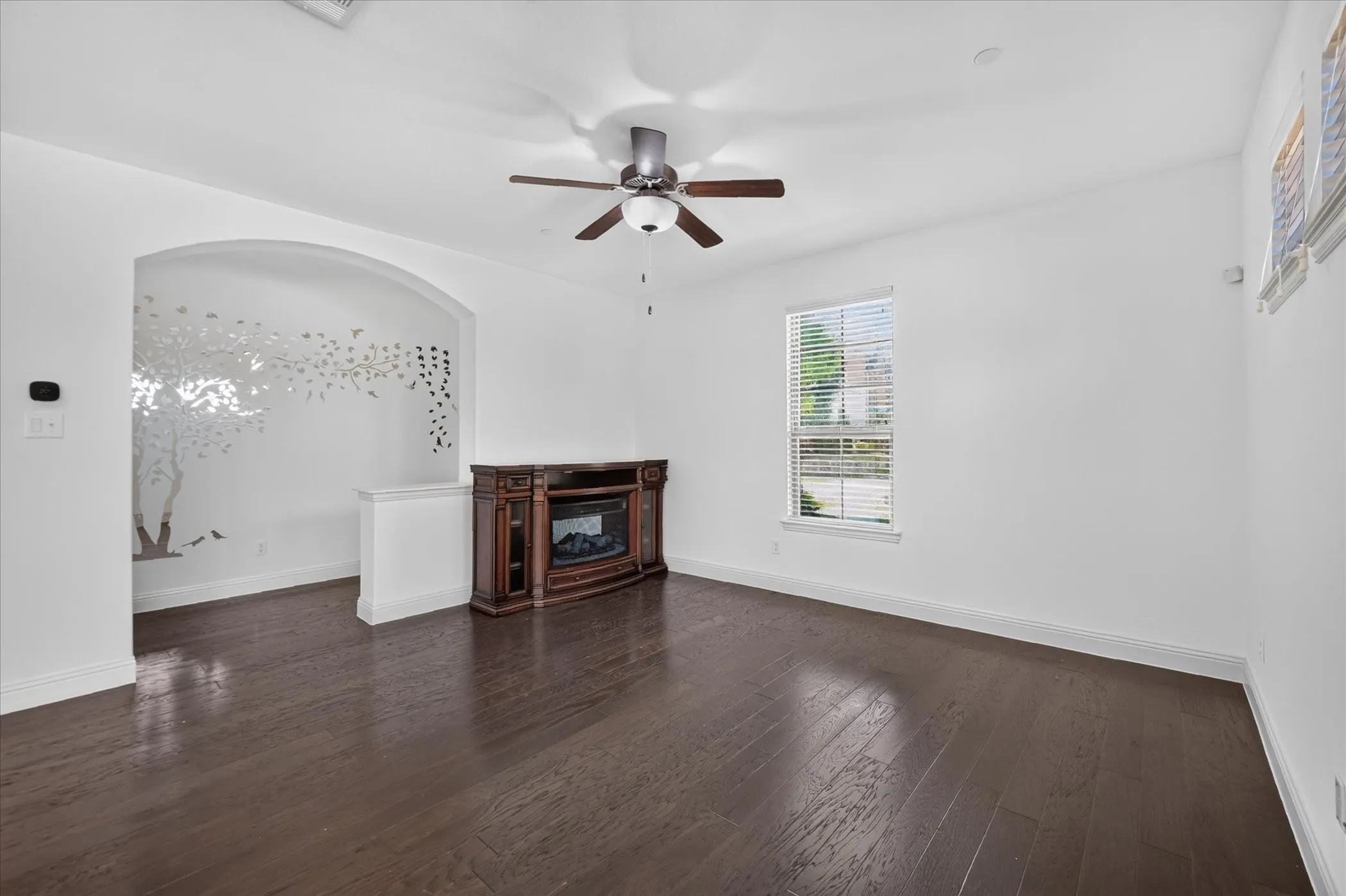 Wood-finish flooring, ceiling fan, and window with blinds
