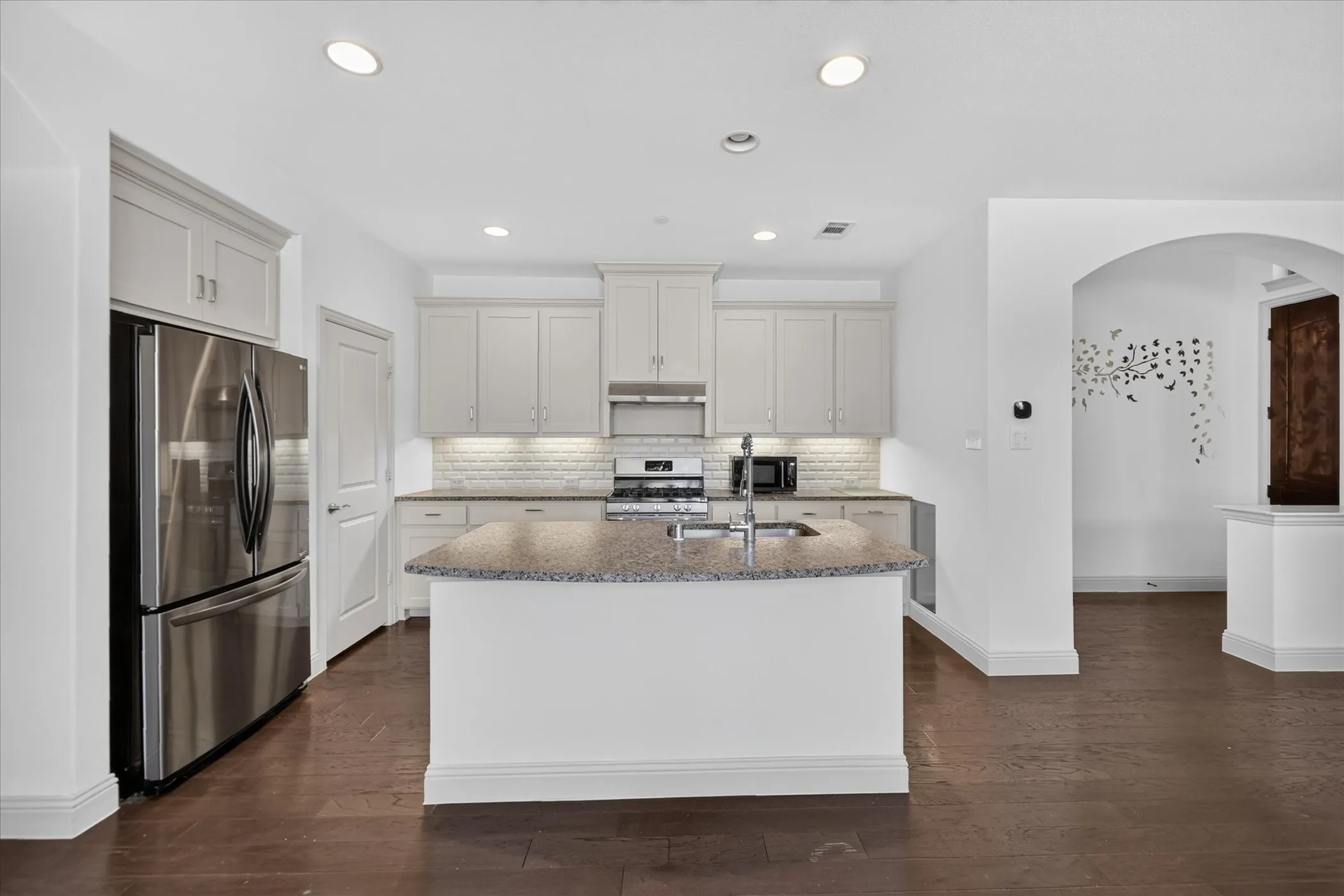 Kitchen featuring a center island, stainless steel appliances, light cabinetry, and wood-finish flooring